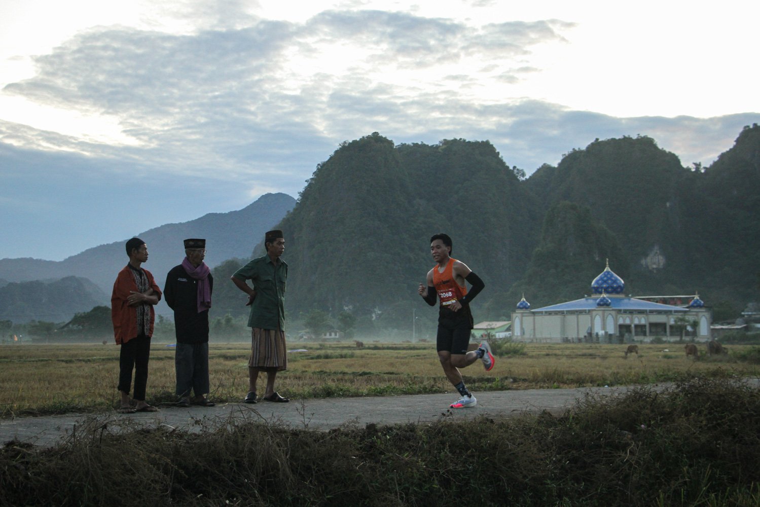 Warga melihat peserta lomba lari Geopark Half Marathon di kawasan Geopark Maros Pangkep di Kecamatan Bantimurung, Kabupaten Maros, Sulawaesi Selatan.