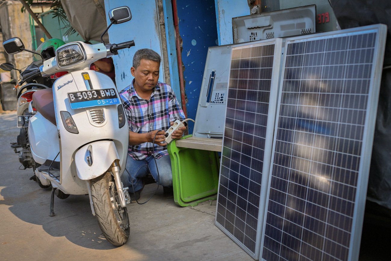 Nurohadi memanfaatkan listrik hasil produksi PLTS yang terpasang di bengkel elektronik miliknya untuk mengisi baterai sepeda motor listrik di Kapuk, Jakarta Barat.