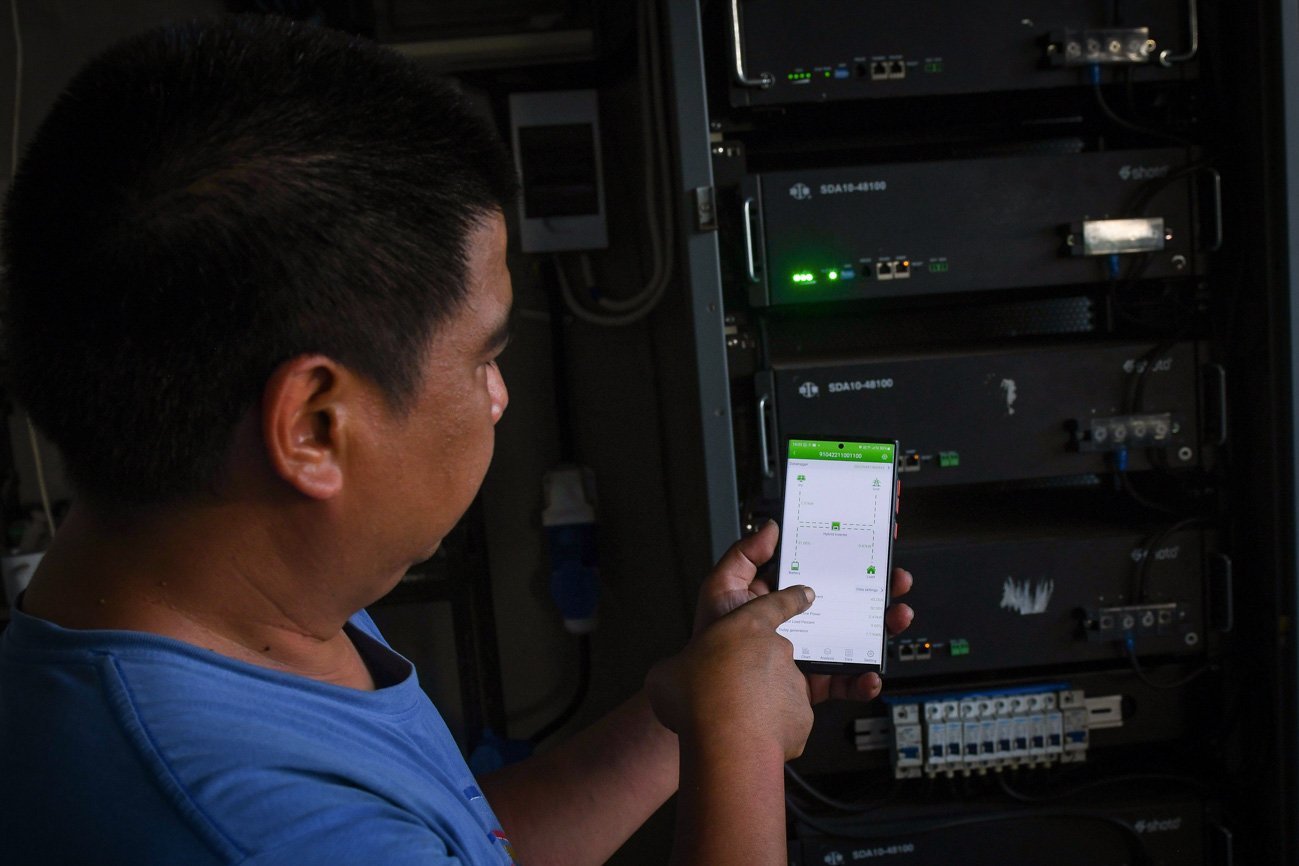 Riky menunjukan cara memantau dan mengontrol sistem PLTS atap miliknya melalui telepon pintar di Duren Sawit, Jakarta Timur.