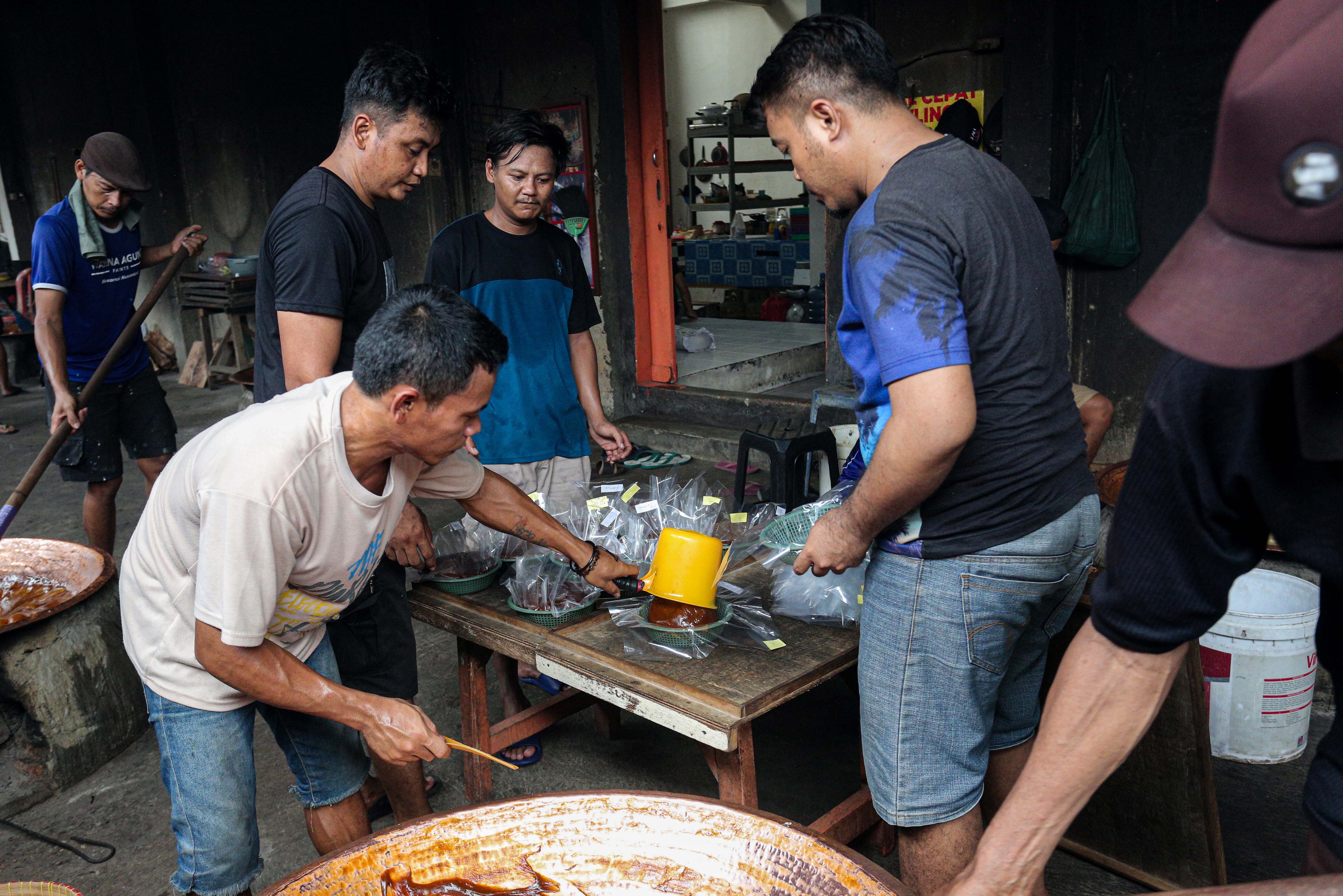 Sejumlah pekerja memindahkan dodol betawi yang sudah matang ke dalam besek di Pondok Dodol Sari Rasa Ibu Yuyun, Pejaten Timur, Pasar Minggu, Jakarta Timur, Rabu (27/3/2024). Dua pekan menjelang Hari Raya Idul Fitri 1445 H, produksi dodol betawi di Pondok Dodol Sari Rasa Ibu Yuyun ini mengalami kenaikan dengan memproduksi 16 keceng (kuali) perharinya.