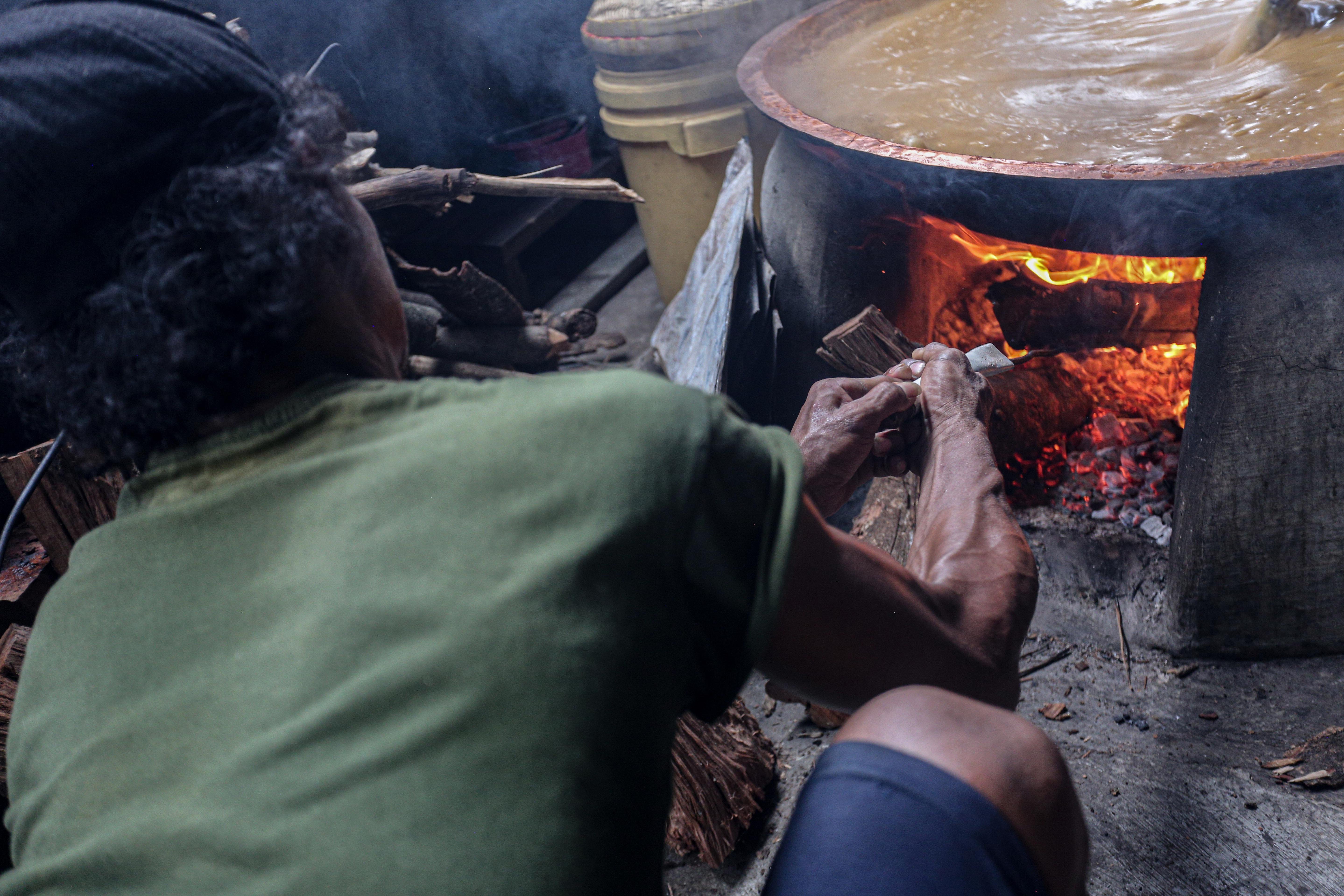 Seorang pekerja menambahkan kayu bakar saat memasak adonan dodol betawi di Pondok Dodol Sari Rasa Ibu Yuyun, Pejaten Timur, Pasar Minggu, Jakarta Timur, Rabu (27/3/2024). Dua pekan menjelang Hari Raya Idul Fitri 1445 H, produksi dodol betawi di Pondok Dodol Sari Rasa Ibu Yuyun ini mengalami kenaikan dengan memproduksi 16 keceng (kuali) perharinya. 
