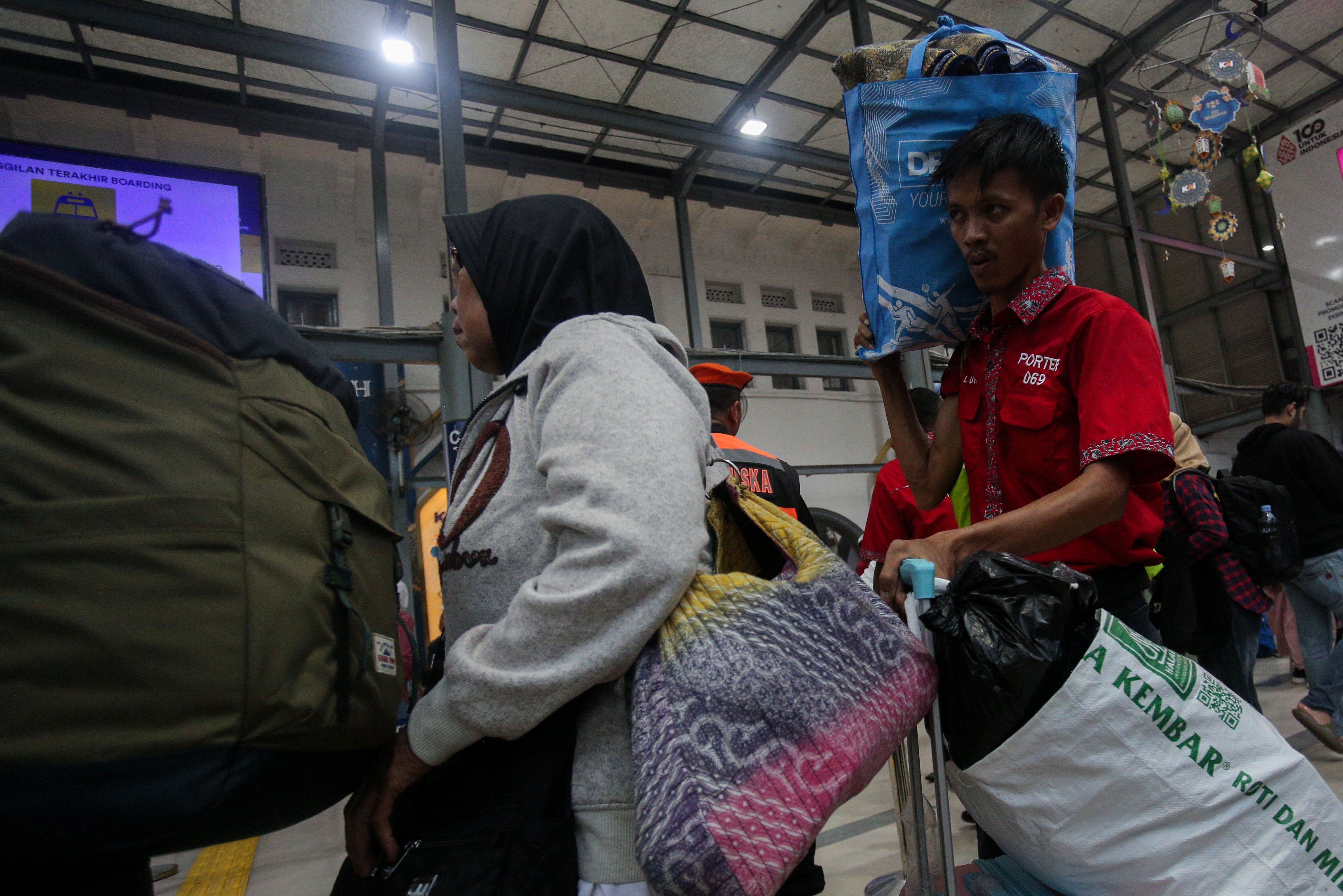 Seorang porter (kanan) membawa barang pemudik di Stasiun Pasar Senen, Jakarta, Rabu (3/4/2024). Pada H-7 menjelang Lebaran, PT Kereta Api Indonesia (Persero) Daop 1 Jakarta memberangkatkan 37 perjalanan kereta api jarak jauh melalui Stasiun Pasar Senen dengan jumlah penumpang sebanyak 26.020.