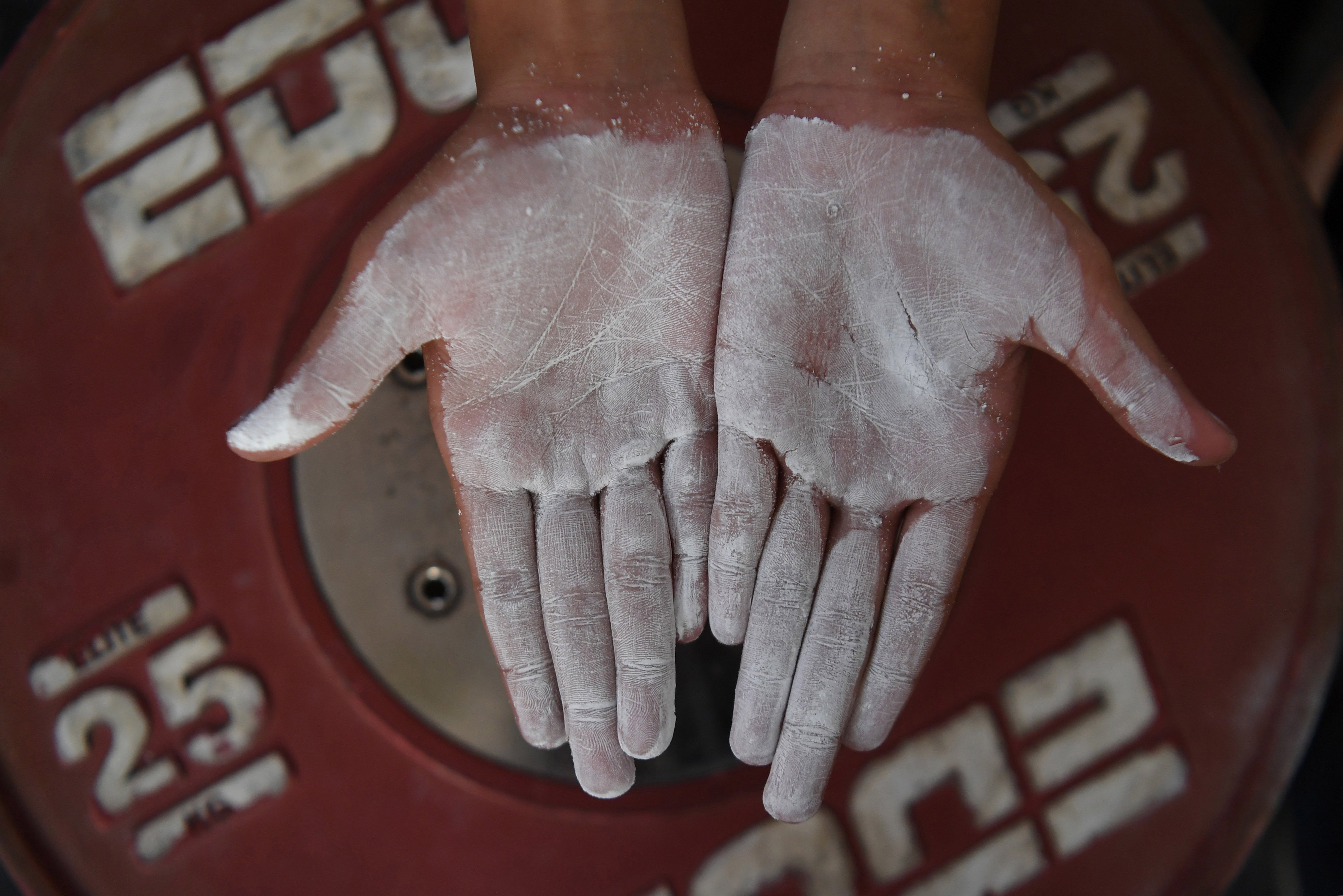 Seorang lifter muda membalurkan bubuk magnesium ke tangannya agar tidak licin di 6221 Weightlifting Academy, Parungpanjang, Bogor, Jawa Barat.