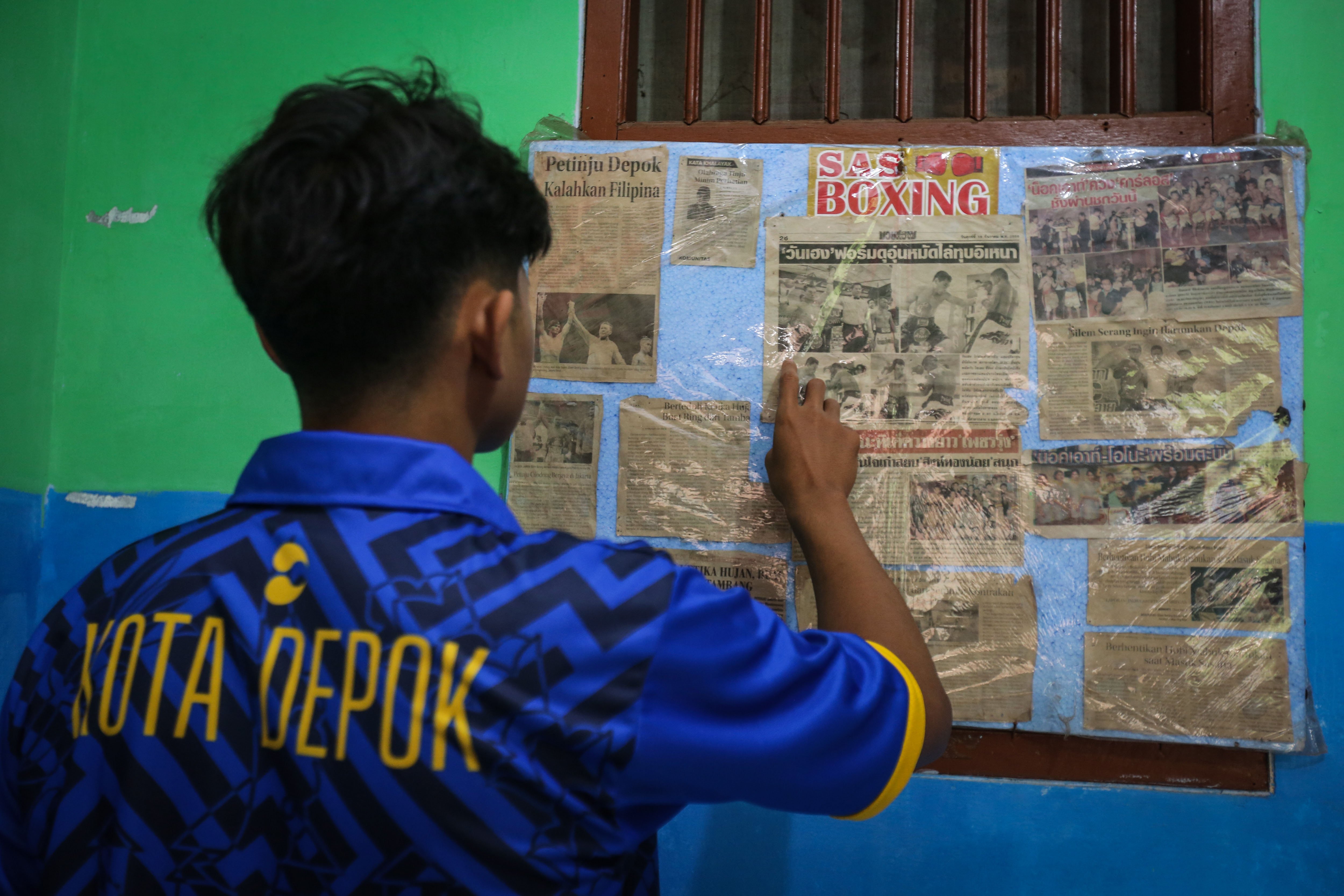 Seorang petinju membaca kumpulan artikel berita tinju di SAS Boxing Depok, Jawa Barat.
