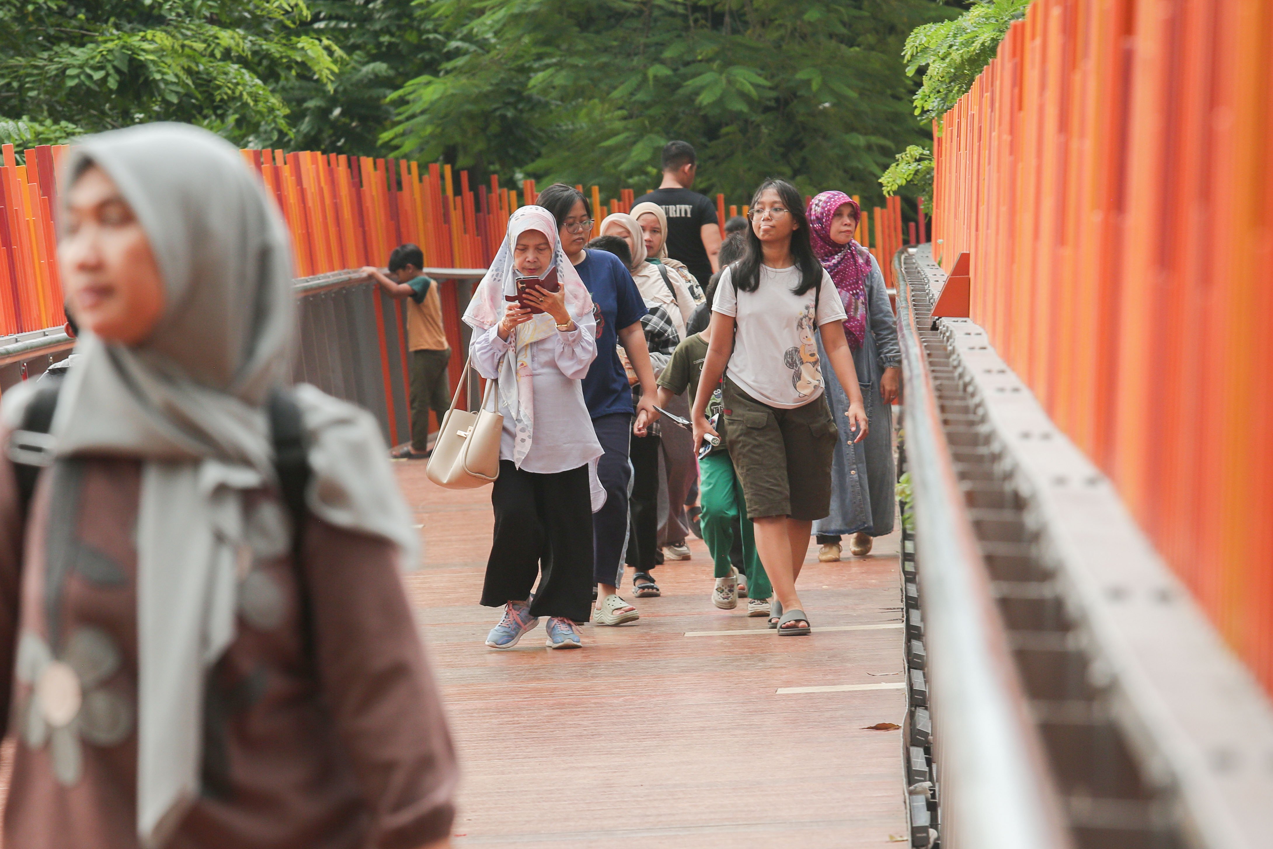 Sejumlah warga berjalan di infinity link bridge Tebet Eco Park, Jakarta, Rabu (3/7/2024). Taman seluas 7,3 hektar yang dikelilingi oleh pepohonan rindang dan menyajikan udara segar ini menjadi salah satu tempat wisata alternatif warga Jakarta dalam menghabiskan waktu liburan sekolah.
