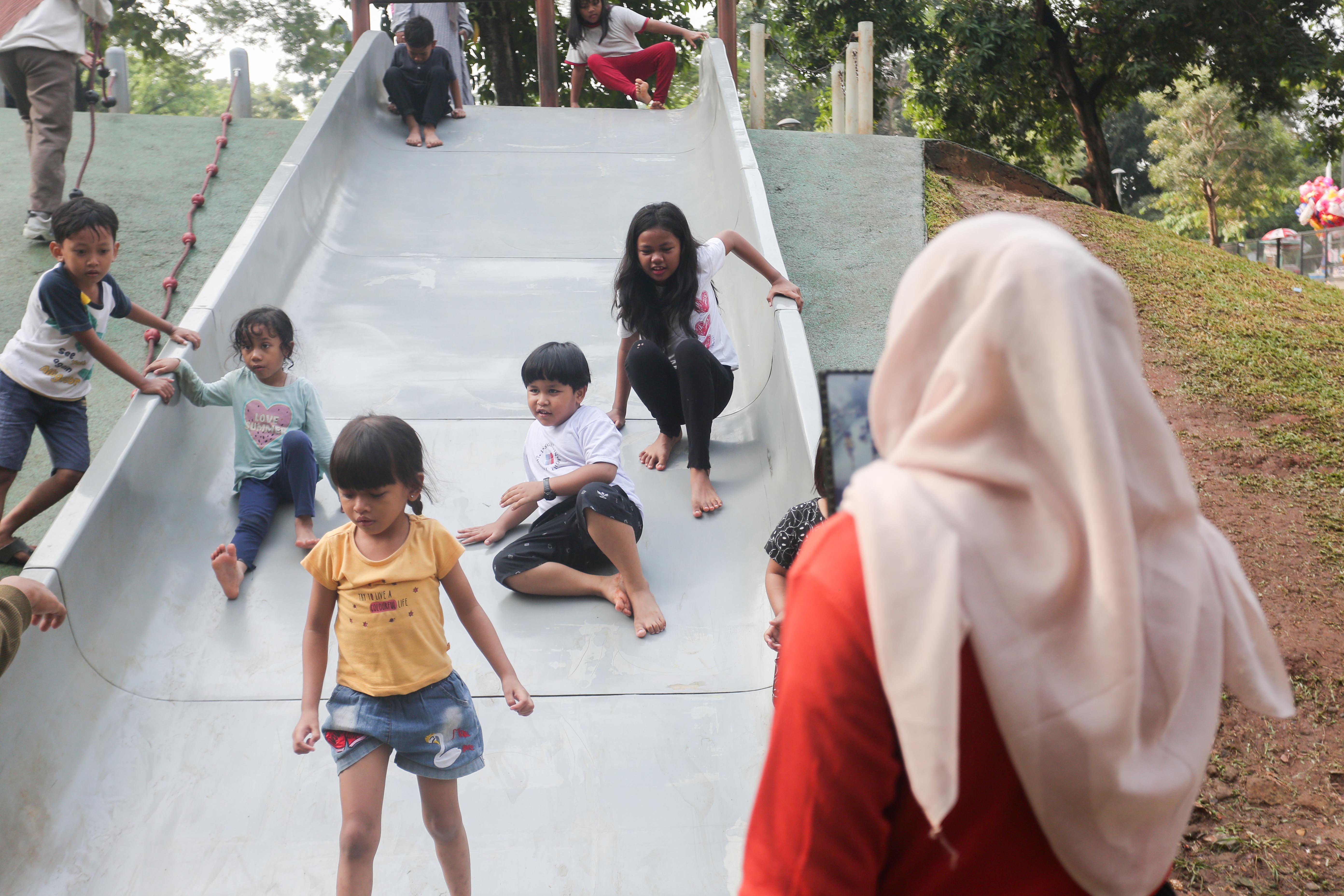 Anak-anak bermain perosotan di taman bermain Tebet Eco Park, Jakarta, Rabu (3/7/2024). Taman seluas 7,3 hektar yang dikelilingi oleh pepohonan rindang dan menyajikan udara segar ini menjadi salah satu tempat wisata alternatif warga Jakarta dalam menghabiskan waktu liburan sekolah.