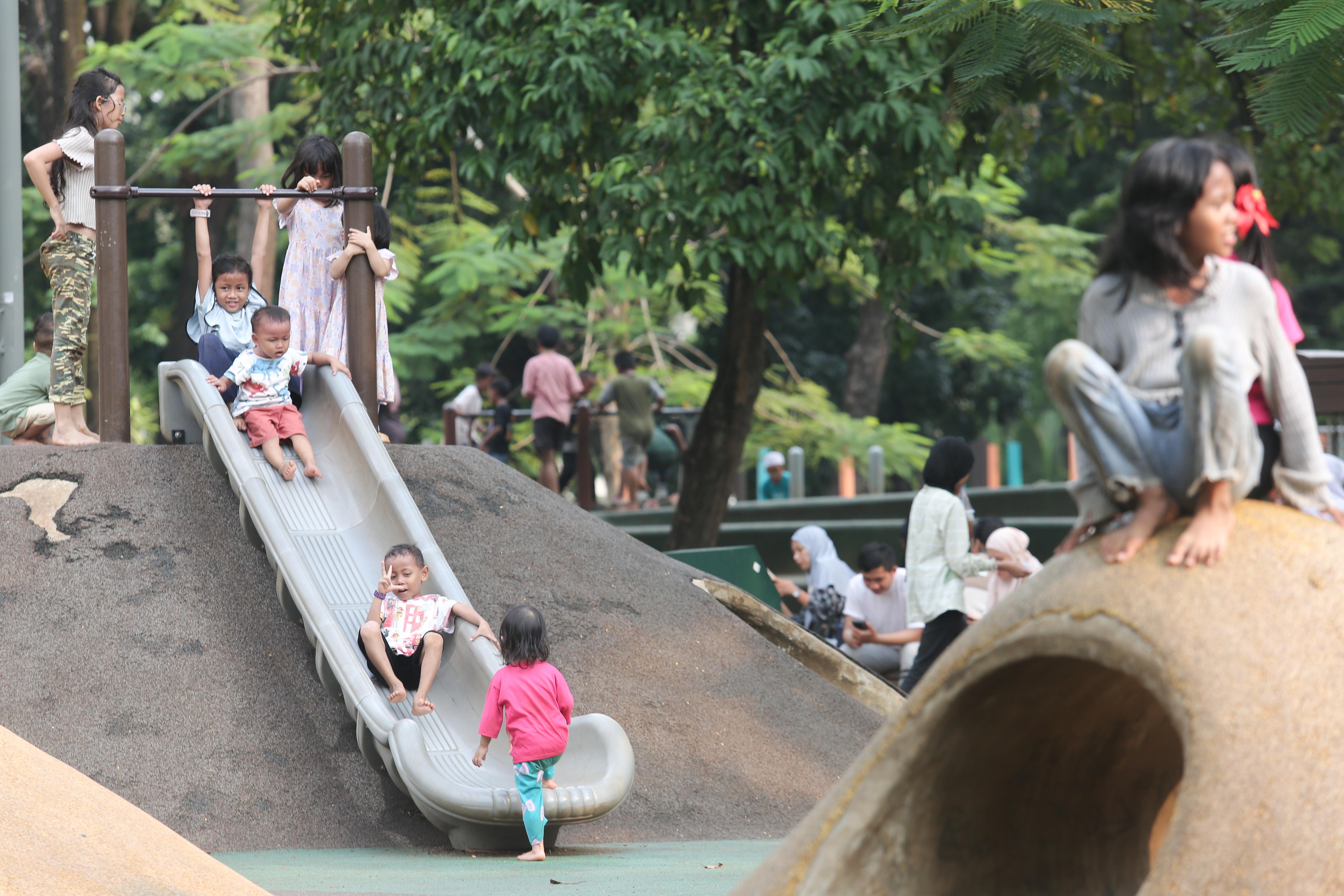 Anak-anak bermain perosotan di taman bermain Tebet Eco Park, Jakarta, Rabu (3/7/2024). Taman seluas 7,3 hektar yang dikelilingi oleh pepohonan rindang dan menyajikan udara segar ini menjadi salah satu tempat wisata alternatif warga Jakarta dalam menghabiskan waktu liburan sekolah.