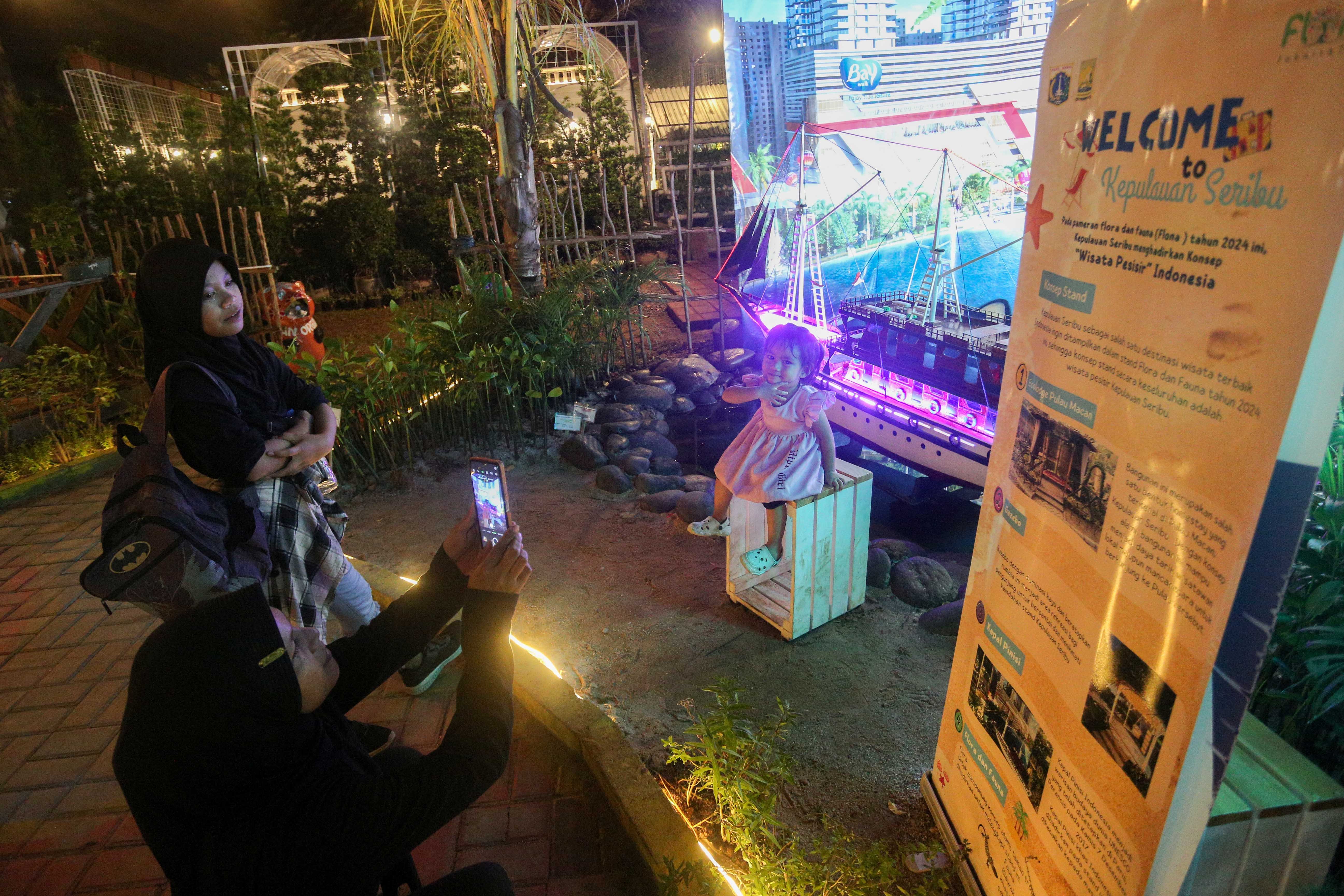 Pengunjung berfoto di stan Kepulauan Seribu saat pameran Flona di Lapangan Banteng, Jakarta, senin (8/7/2024). Pameran yang mengusung tema Jakarta Global Hijau Mempesona ini menampilkan berbagai jenis tanaman hias, hewan peliharaan dan kuliner nusantara yang berlangsung hingga 2 Agustus 2024.