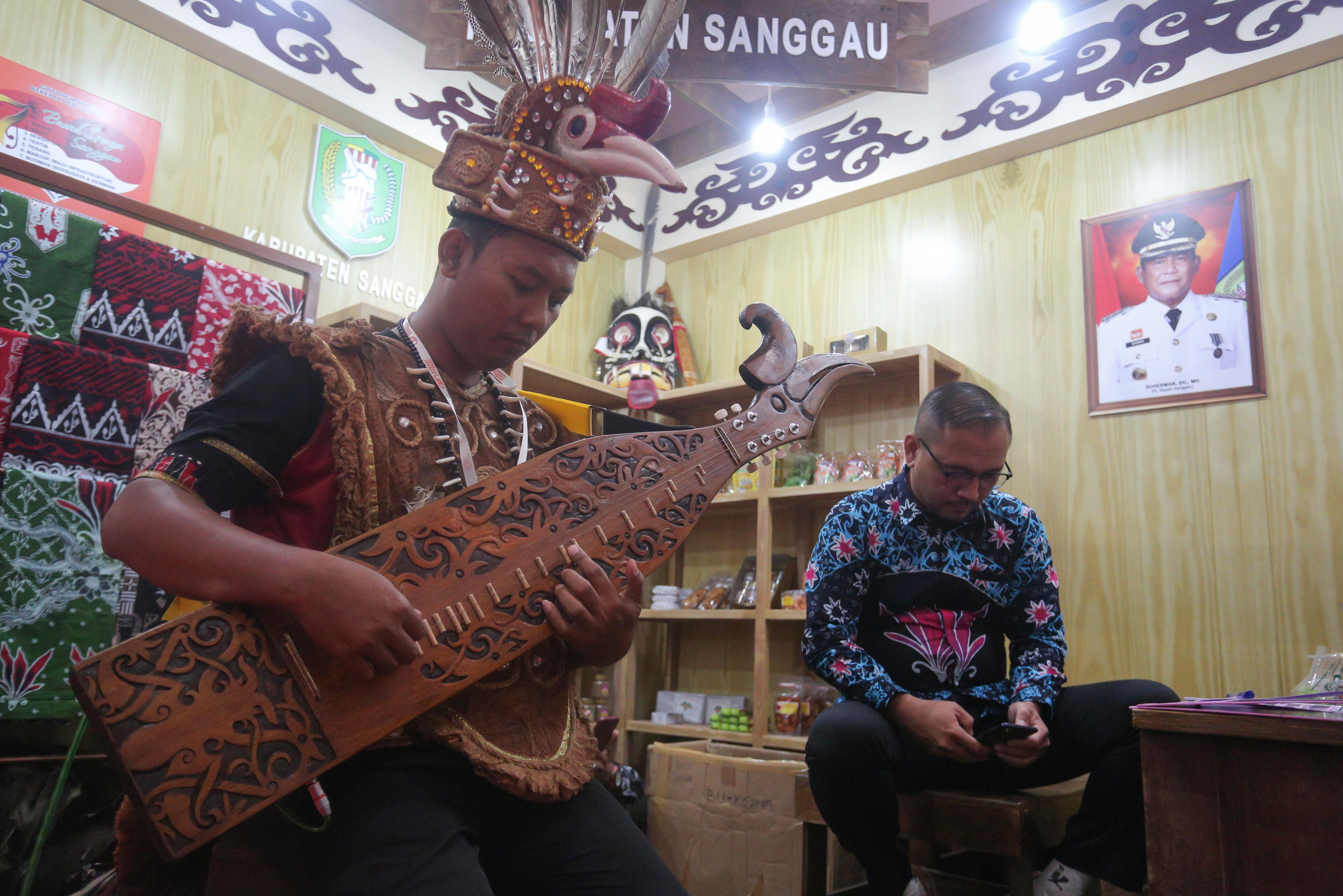 Seniman memainkan alat musik sape saat pameran Asosiasi Kabupaten Seluruh Indonesia (Apkasi) Otonomi Expo 2024 di Jakarta Convention Center (JCC), Senayan, Jakarta, Rabu (10/7/2024). Pameran yang mengangkat tema \