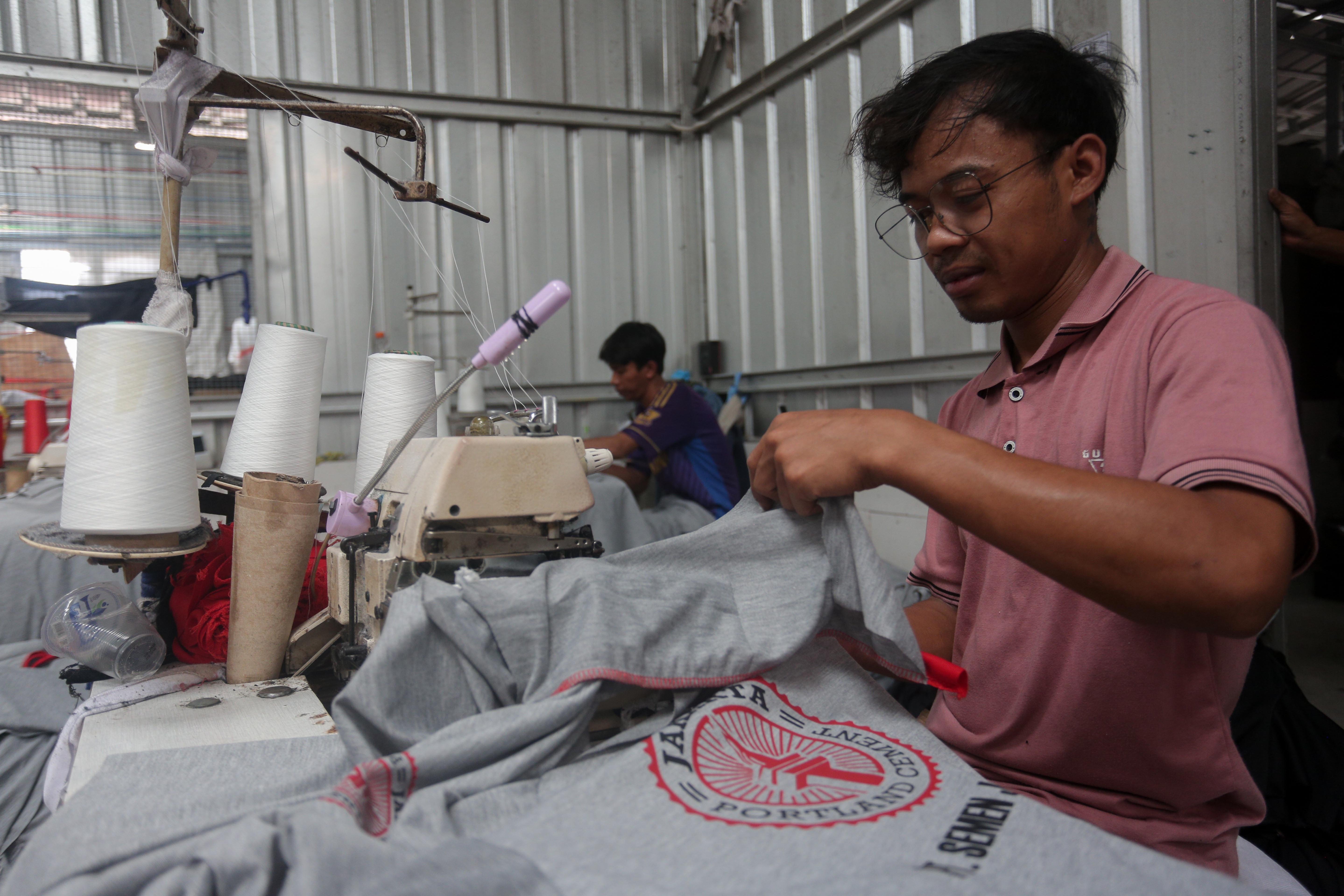 Pekerja menyelesaikan pembuatan kaos di konveksi Sinergi Adv Nusantara di kawasan Srengseng Sawah, Jakarta Selatan, Rabu (17/7/2024). Di tengah maraknya produk impor di pasaran yang mengakibatkan industri tekstil dalam negeri terpuruk, usaha konveksi masih bertahan dengan memenuhi pesanan sekitar 500 ribu kaos per bulan.