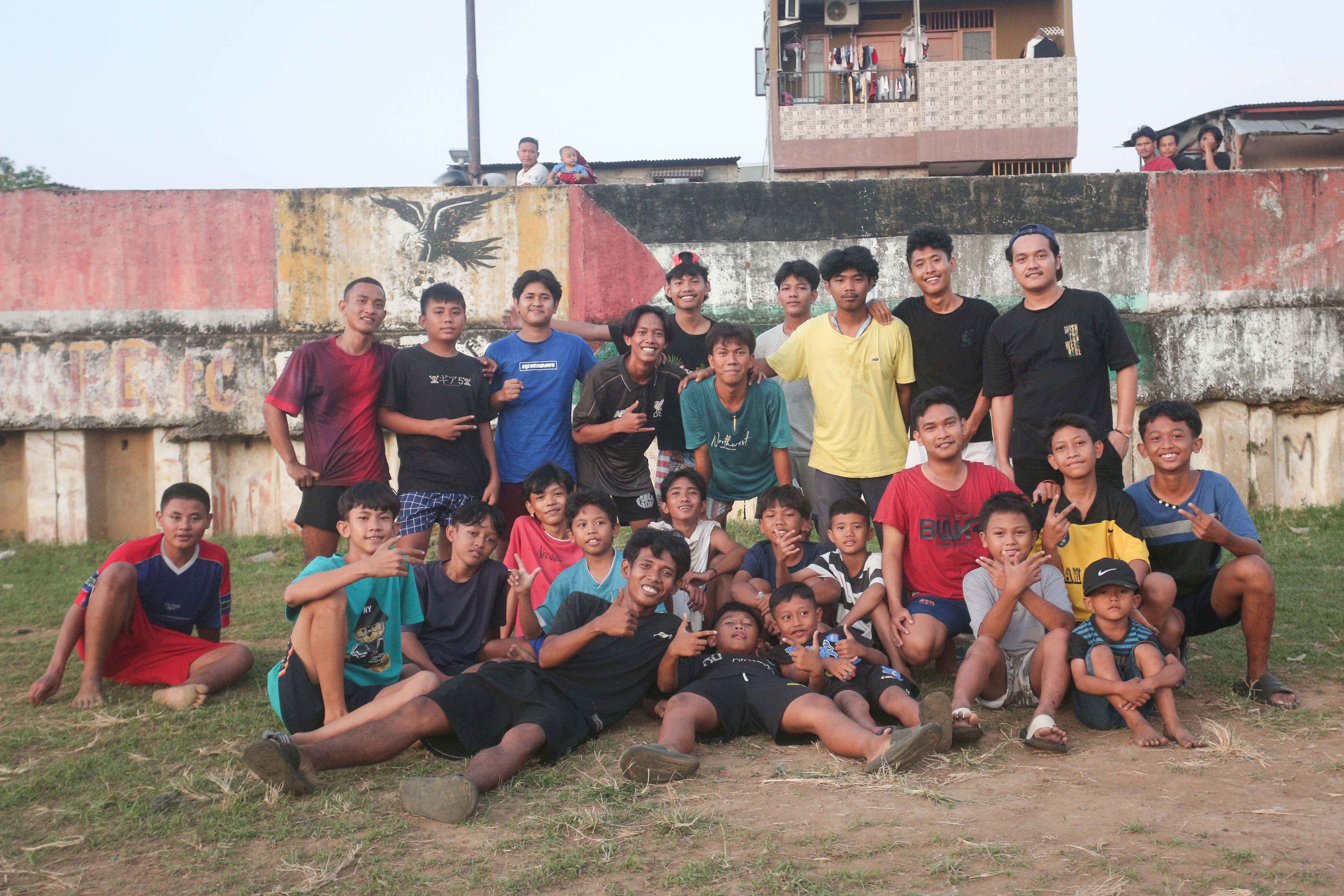 Sejumlah warga berfoto bersama setelah bermain sepak bola di bantaran Kali Ciliwung di Jalan Setia Kawan III, Duri Pulo, Jakarta Pusat, Selasa (16/7/2024). Terbatasnya ruang terbuka hijau (RTH) di sekitar wilayah tersebut membuat warga memanfaatkan lahan kosong di bantaran kali untuk bermain sepak bola.