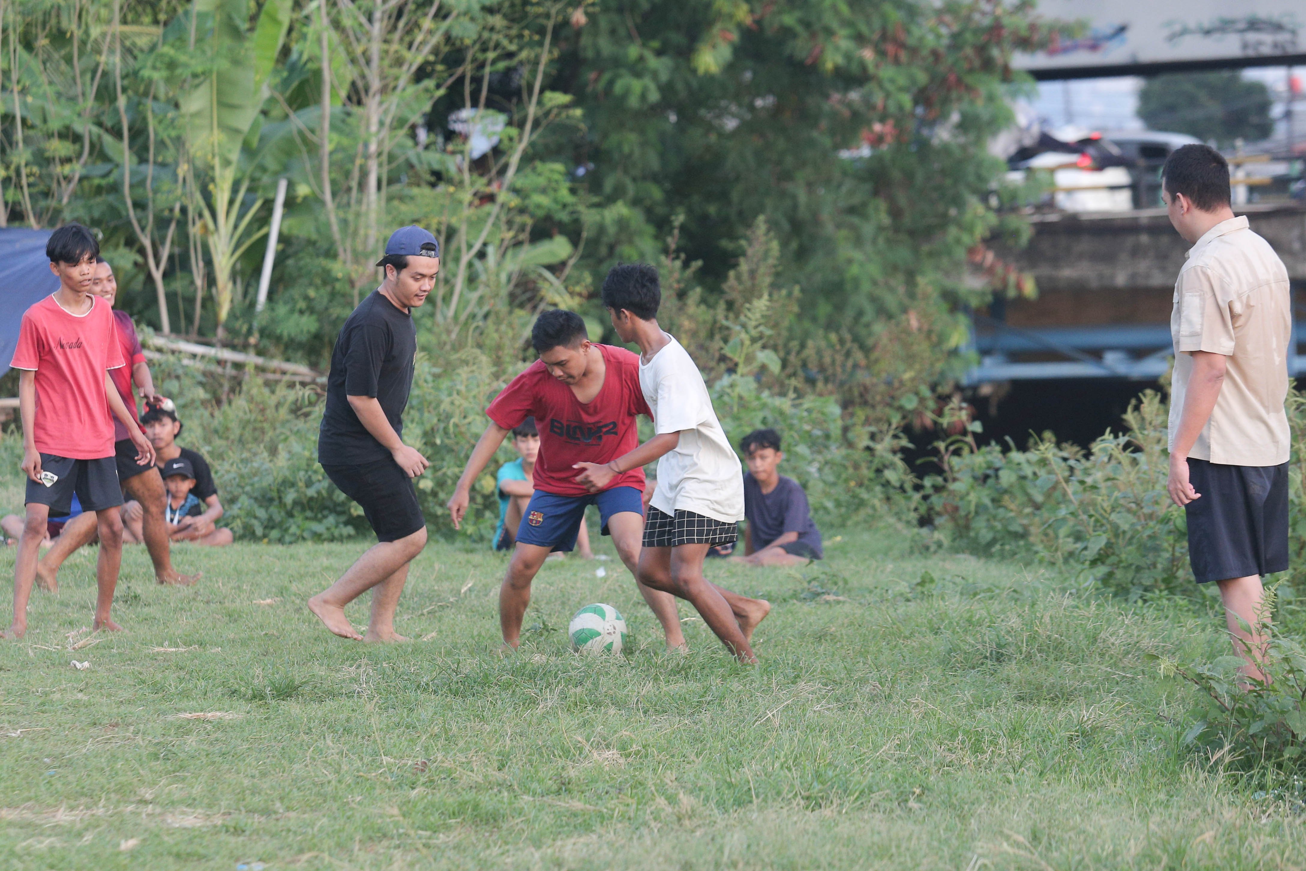 Sejumlah warga bermain sepak bola di bantaran Kali Ciliwung di Jalan Setia Kawan III, Duri Pulo, Jakarta Pusat, Selasa (16/7/2024). Terbatasnya ruang terbuka hijau (RTH) di sekitar wilayah tersebut membuat warga memanfaatkan lahan kosong di bantaran kali untuk bermain sepak bola.