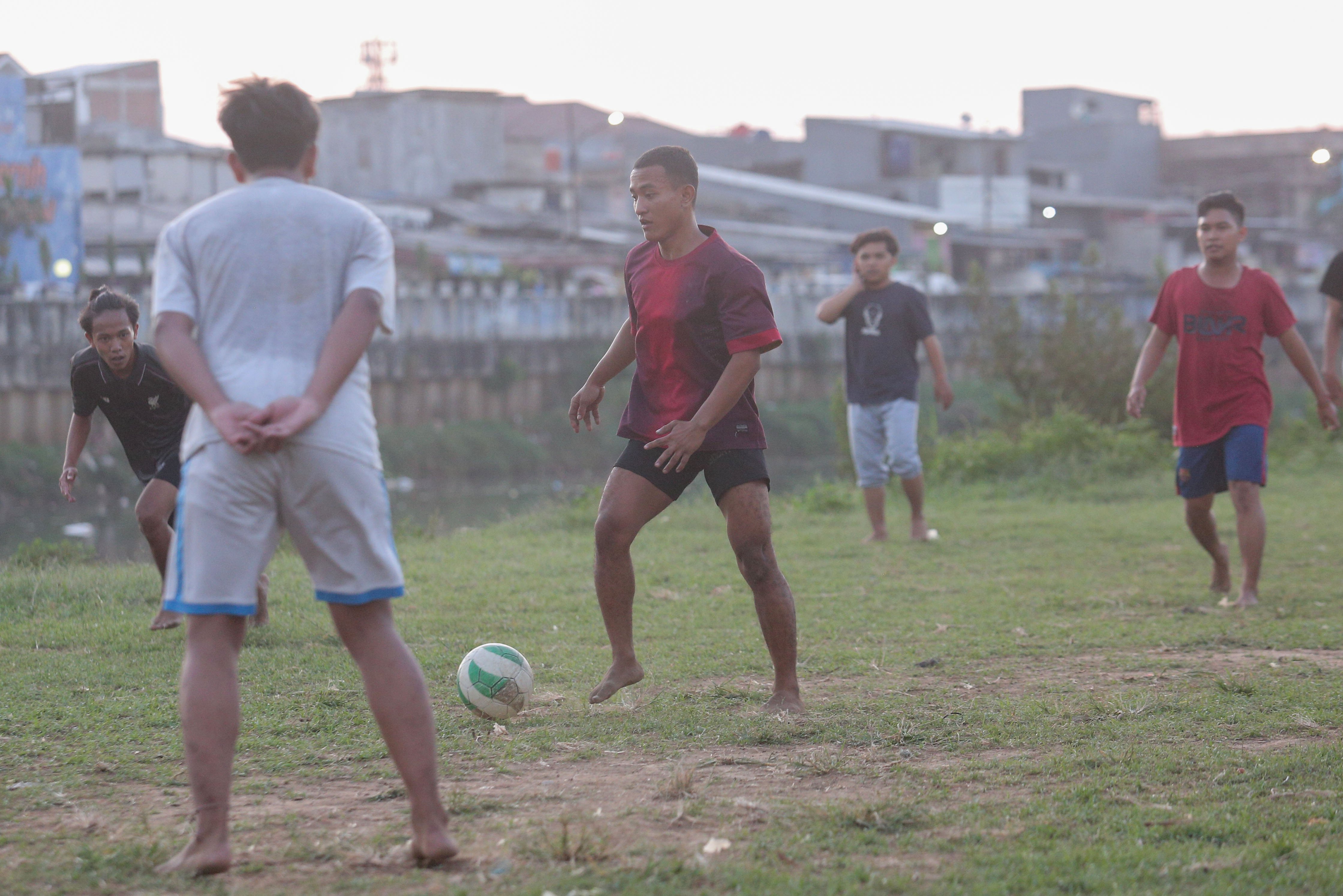 Sejumlah warga bermain sepak bola di bantaran Kali Ciliwung di Jalan Setia Kawan III, Duri Pulo, Jakarta Pusat, Selasa (16/7/2024). Terbatasnya ruang terbuka hijau (RTH) di sekitar wilayah tersebut membuat warga memanfaatkan lahan kosong di bantaran kali untuk bermain sepak bola.