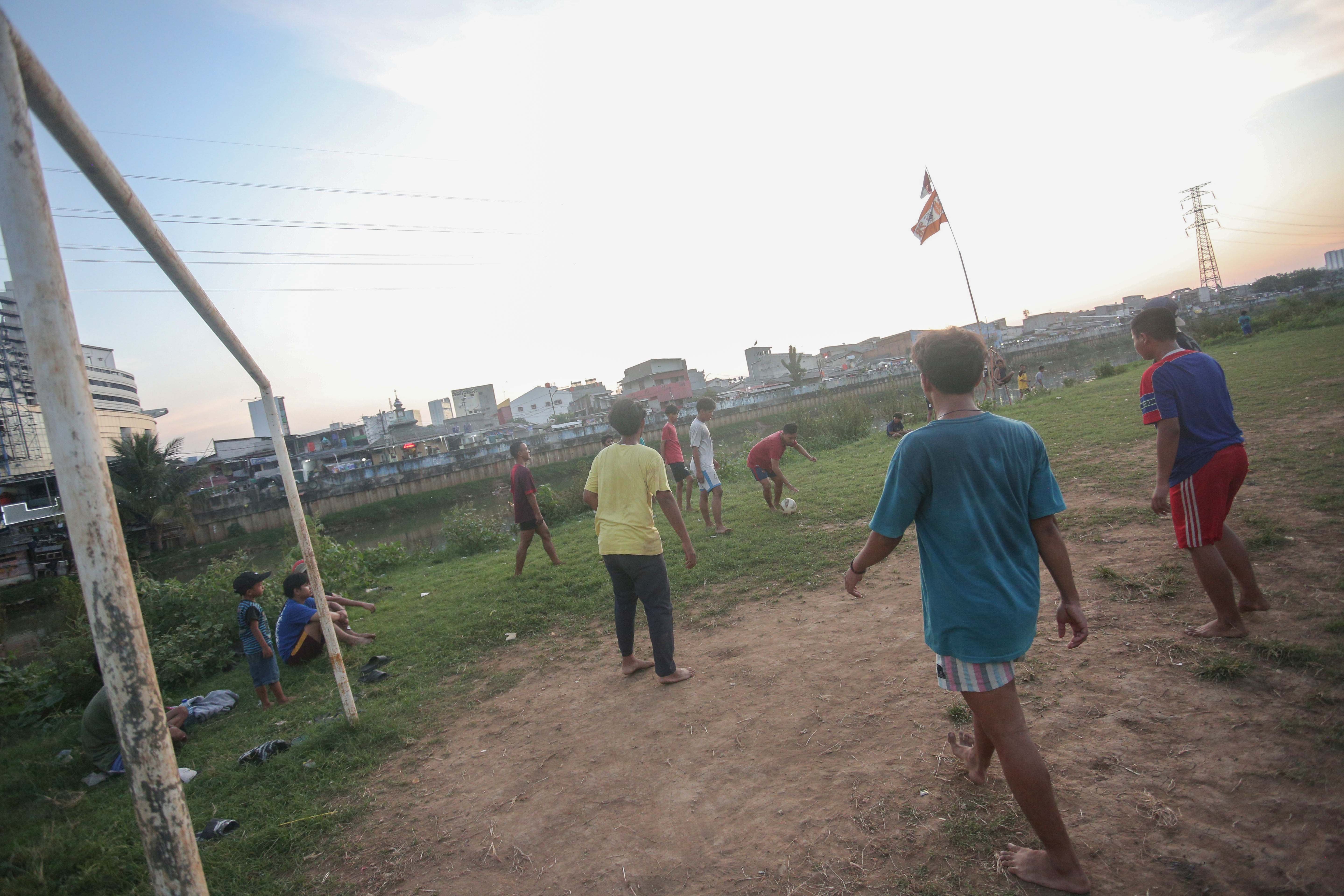 Sejumlah warga bermain sepak bola di bantaran Kali Ciliwung di Jalan Setia Kawan III, Duri Pulo, Jakarta Pusat, Selasa (16/7/2024). Terbatasnya ruang terbuka hijau (RTH) di sekitar wilayah tersebut membuat warga memanfaatkan lahan kosong di bantaran kali untuk bermain sepak bola.