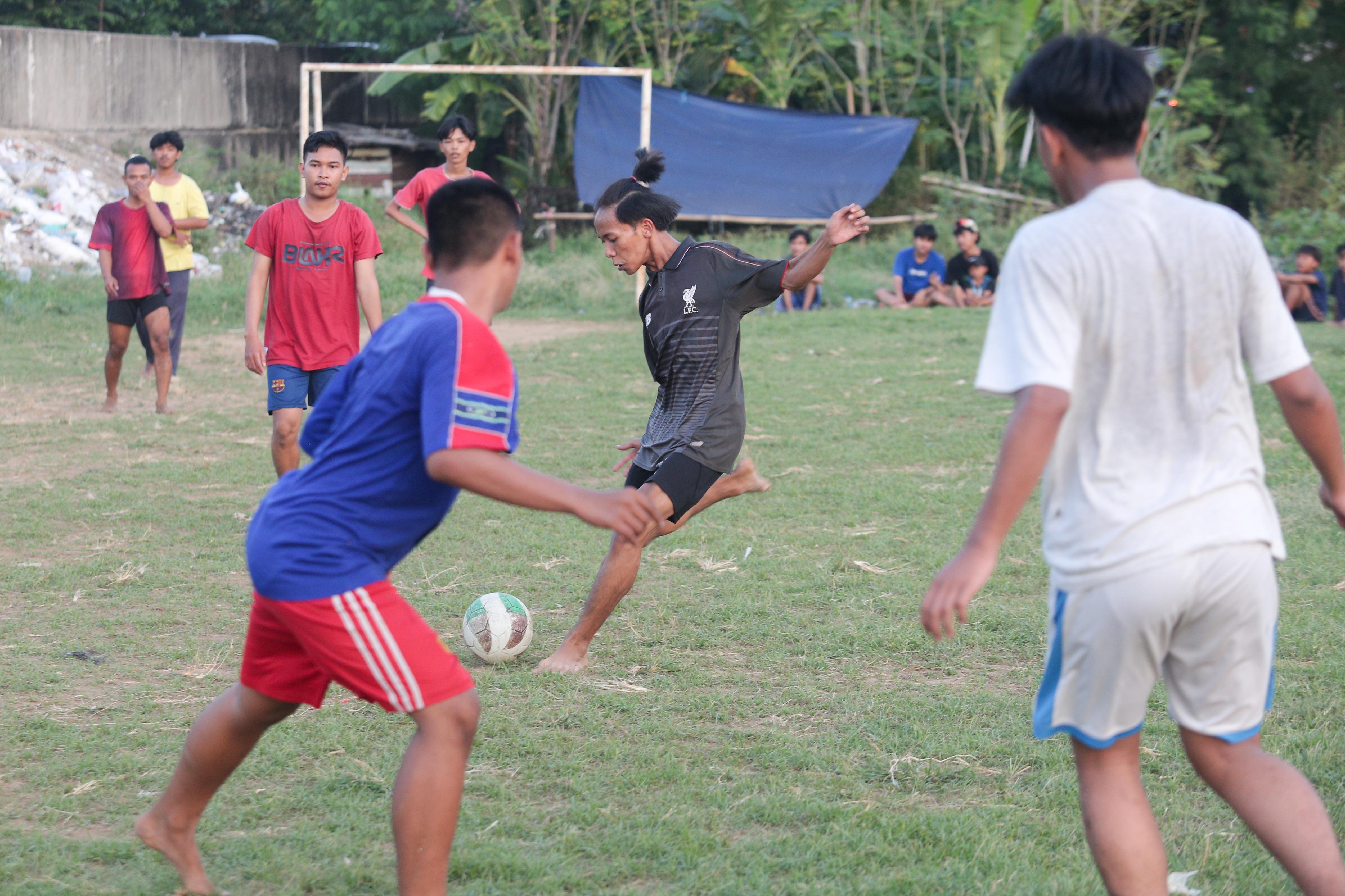 Sejumlah warga bermain sepak bola di bantaran Kali Ciliwung di Jalan Setia Kawan III, Duri Pulo, Jakarta Pusat, Selasa (16/7/2024). Terbatasnya ruang terbuka hijau (RTH) di sekitar wilayah tersebut membuat warga memanfaatkan lahan kosong di bantaran kali untuk bermain sepak bola.