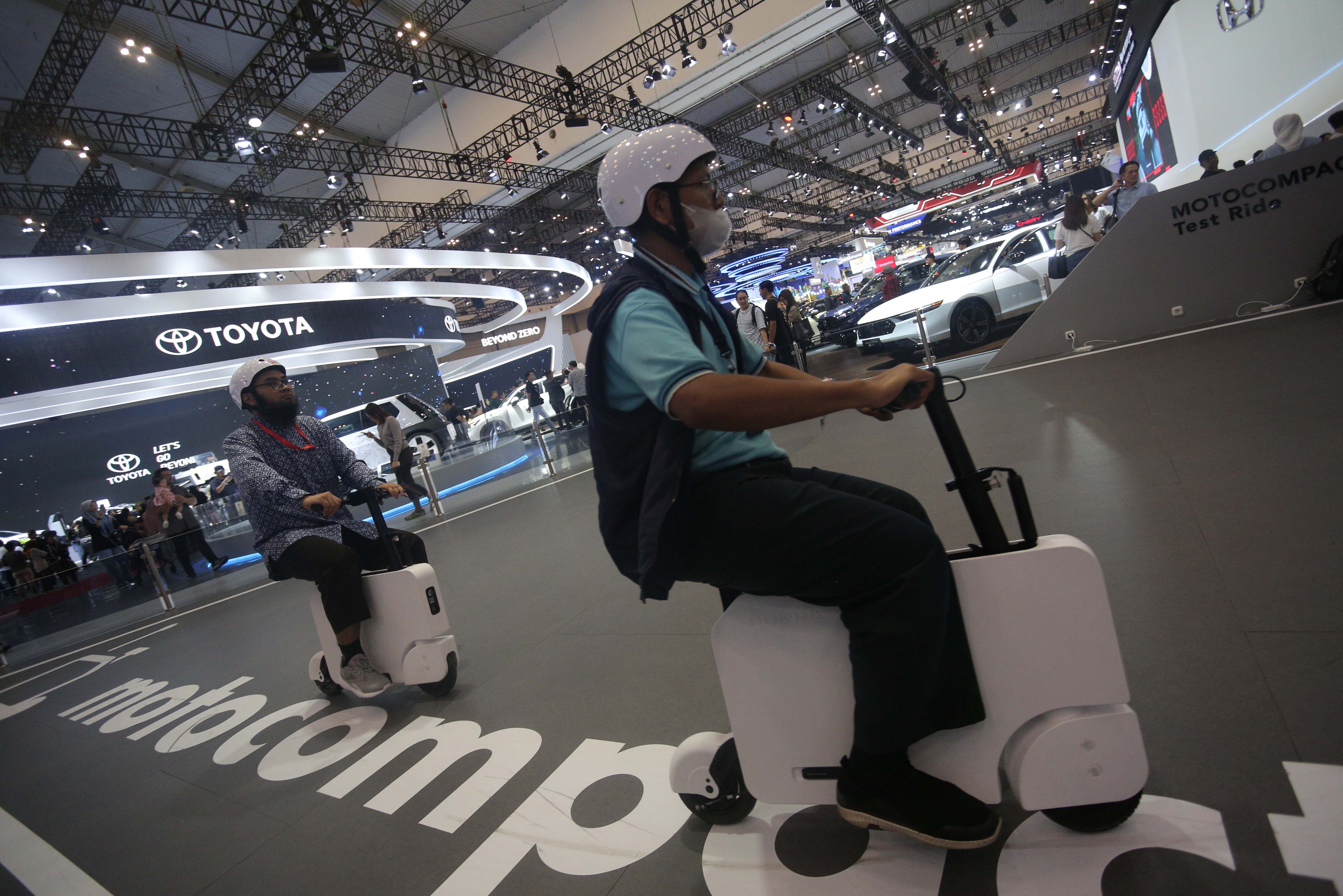 Dua orang pengunjung mencoba motor listrik Honda Motocompacto pada GAIKINDO Indonesia International Auto Show (GIIAS) 2024 di ICE BSD City, Kabupaten Tangerang, Banten, Jumat (19/7/2024). Pameran otomotif yang mengusung tema \