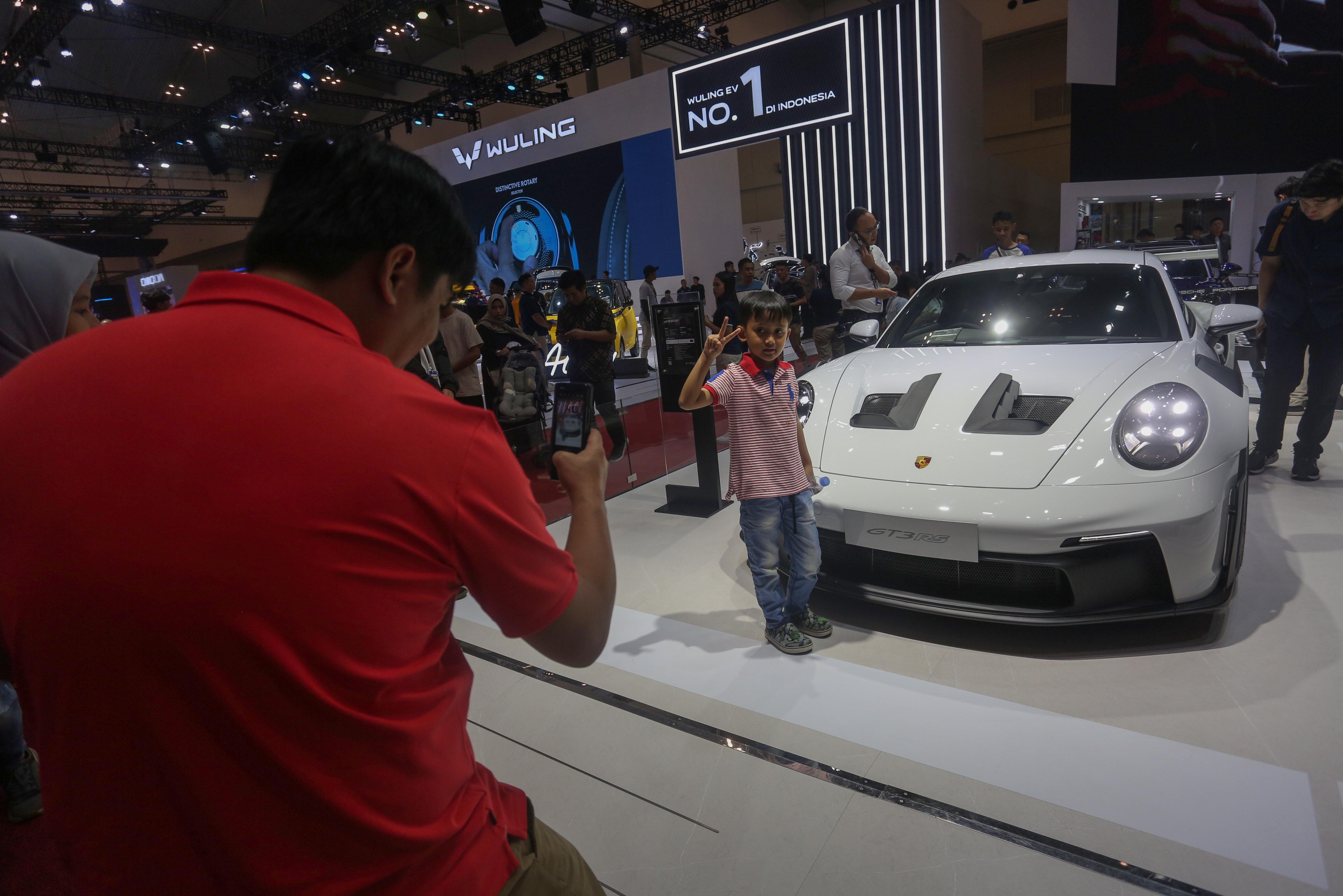 Seorang anak berfoto dengan mobil Porsche GT3 RS yang dipamerkan di GAIKINDO Indonesia International Auto Show (GIIAS) 2024 di ICE BSD City, Kabupaten Tangerang, Banten, Jumat (19/7/2024). Pameran otomotif yang mengusung tema \