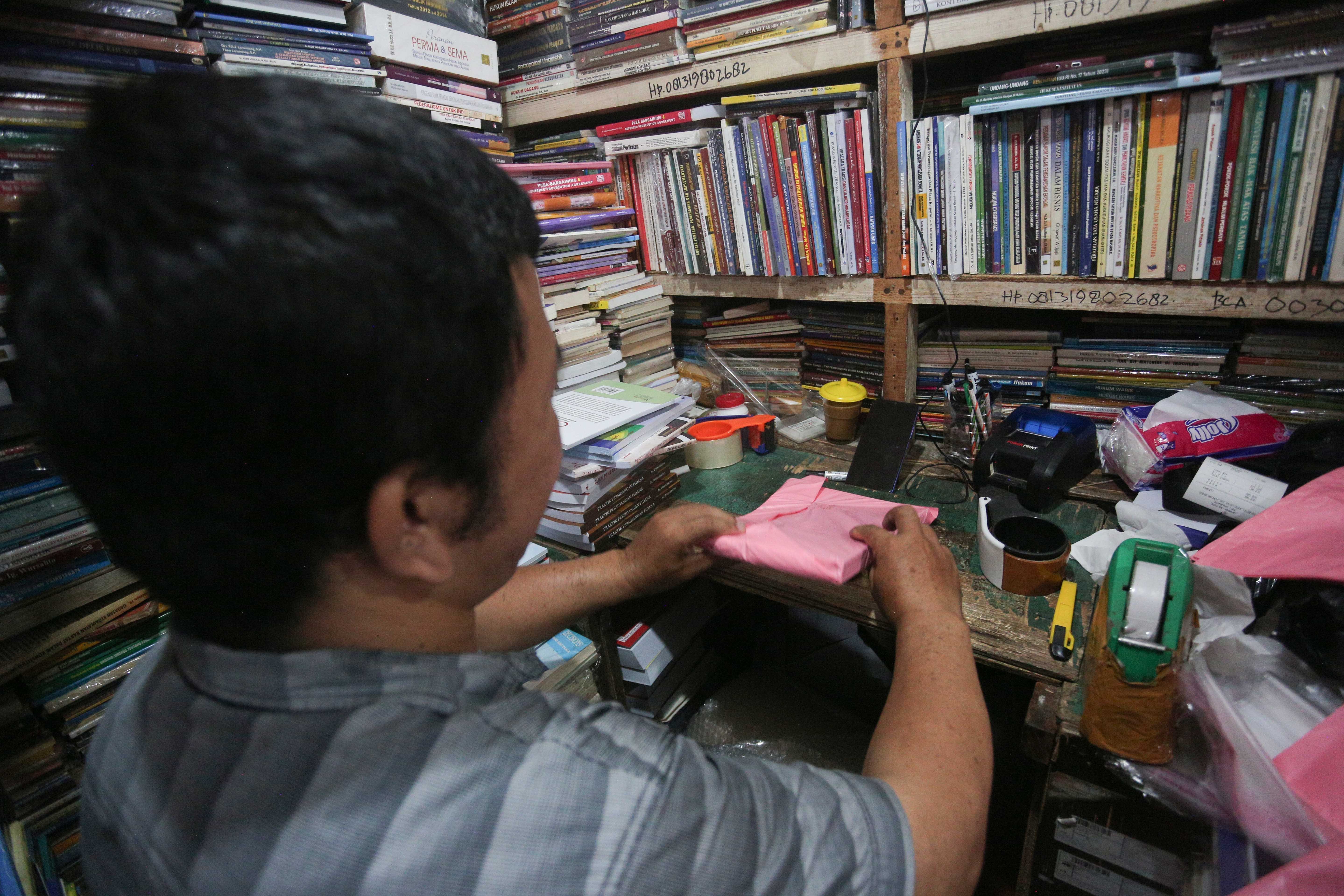 Pedagang mengemas buku yang akan dikirimkan kepada pembeli di Pasar Buku Kwitang, Jakarta Pusat, Rabu (24/7/2024). Berdasarkan penuturan pedagang, berkembangnya teknologi membuat masyarakat beralih dari membaca buku fisik ke digital sehingga penjualan buku di pasar tersebut mengalami penurunan yang cukup signifikan.