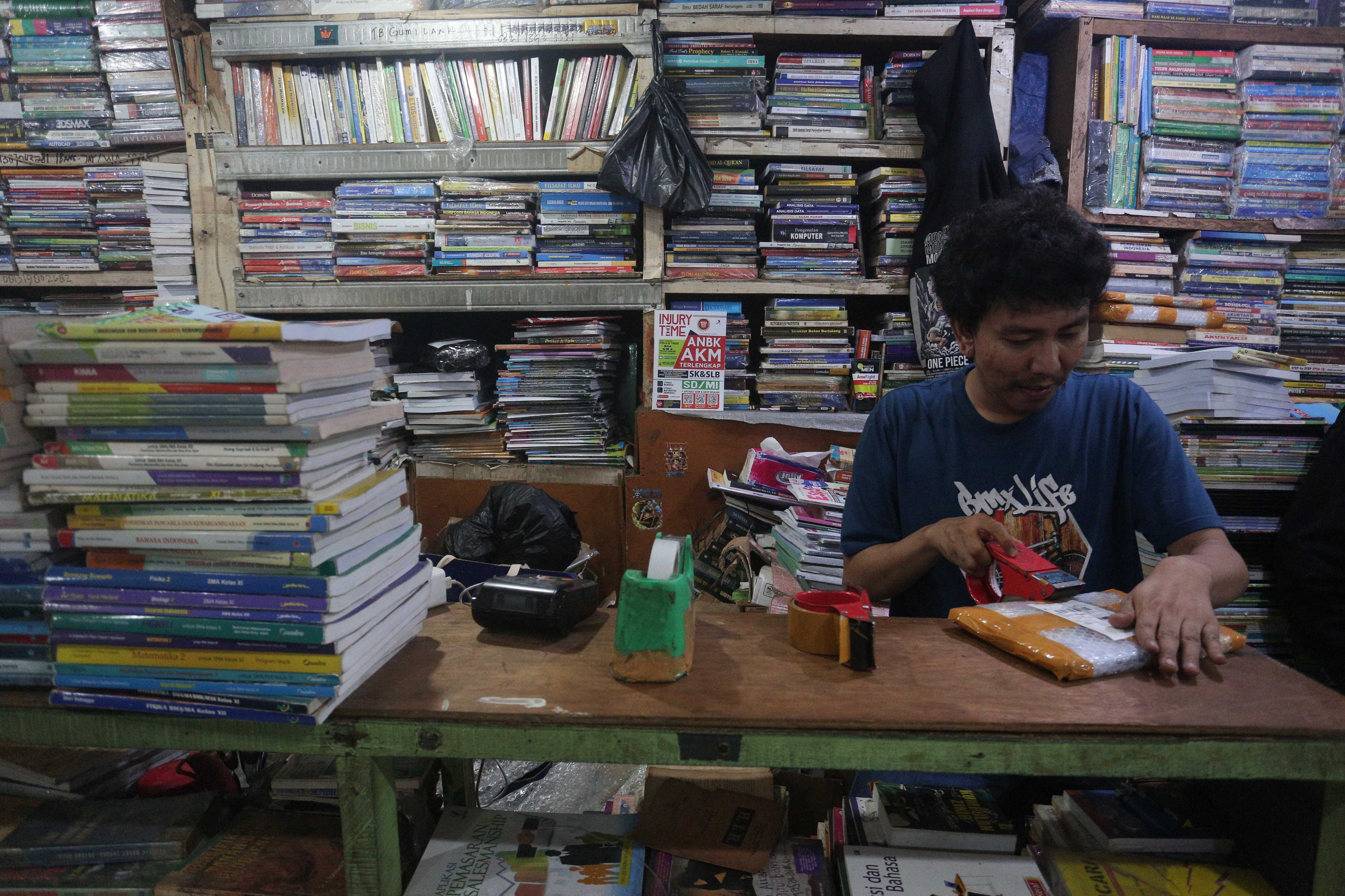 Pedagang mengemas buku yang akan dikirimkan kepada pembeli di Pasar Buku Kwitang, Jakarta Pusat, Rabu (24/7/2024). Berdasarkan penuturan pedagang, berkembangnya teknologi membuat masyarakat beralih dari membaca buku fisik ke digital sehingga penjualan buku di pasar tersebut mengalami penurunan yang cukup signifikan.