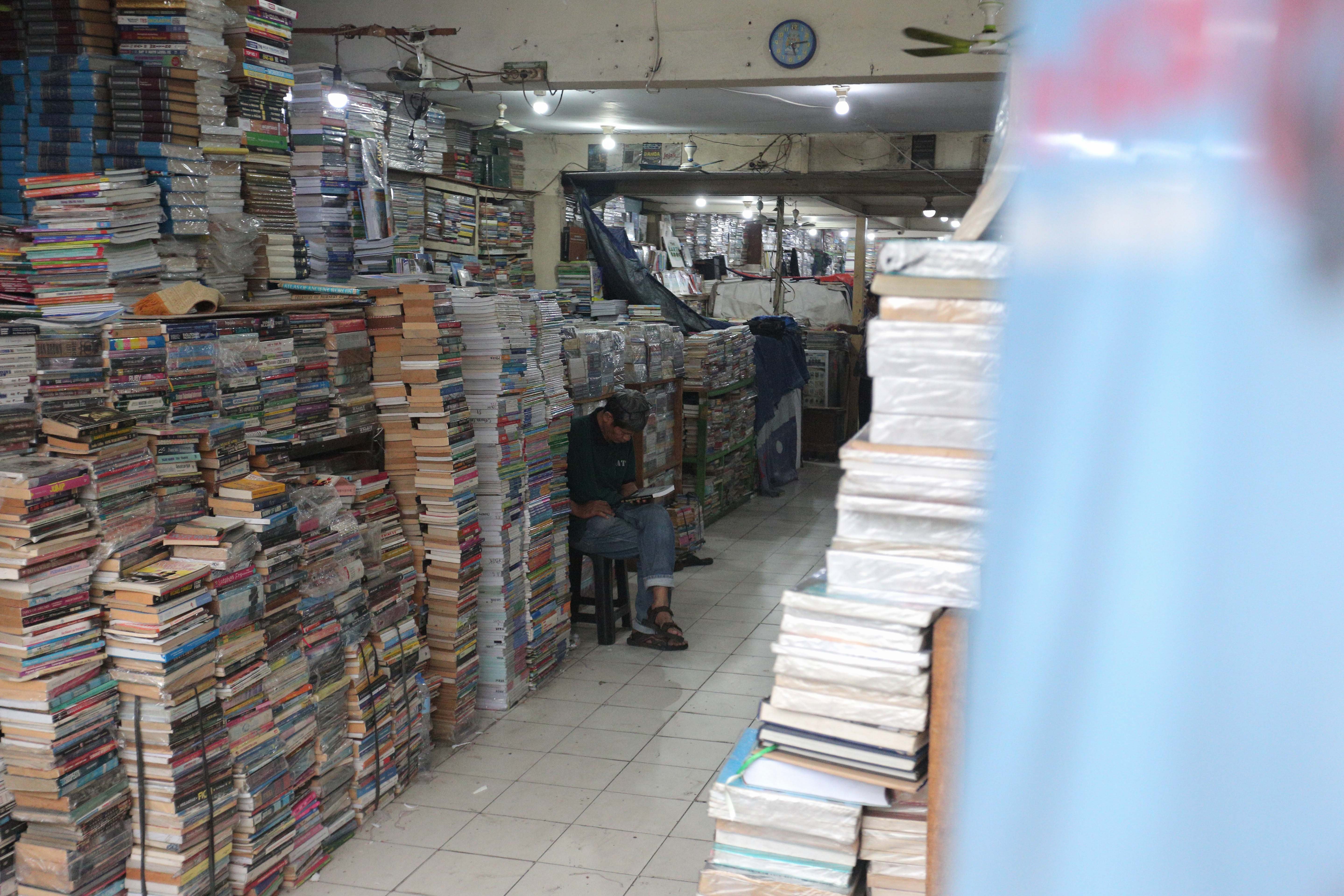 Pedagang melihat buku yang dijual di Pasar Buku Kwitang, Jakarta Pusat, Rabu (24/7/2024). Berdasarkan penuturan pedagang, berkembangnya teknologi membuat masyarakat beralih dari membaca buku fisik ke digital sehingga penjualan buku di pasar tersebut mengalami penurunan yang cukup signifikan.