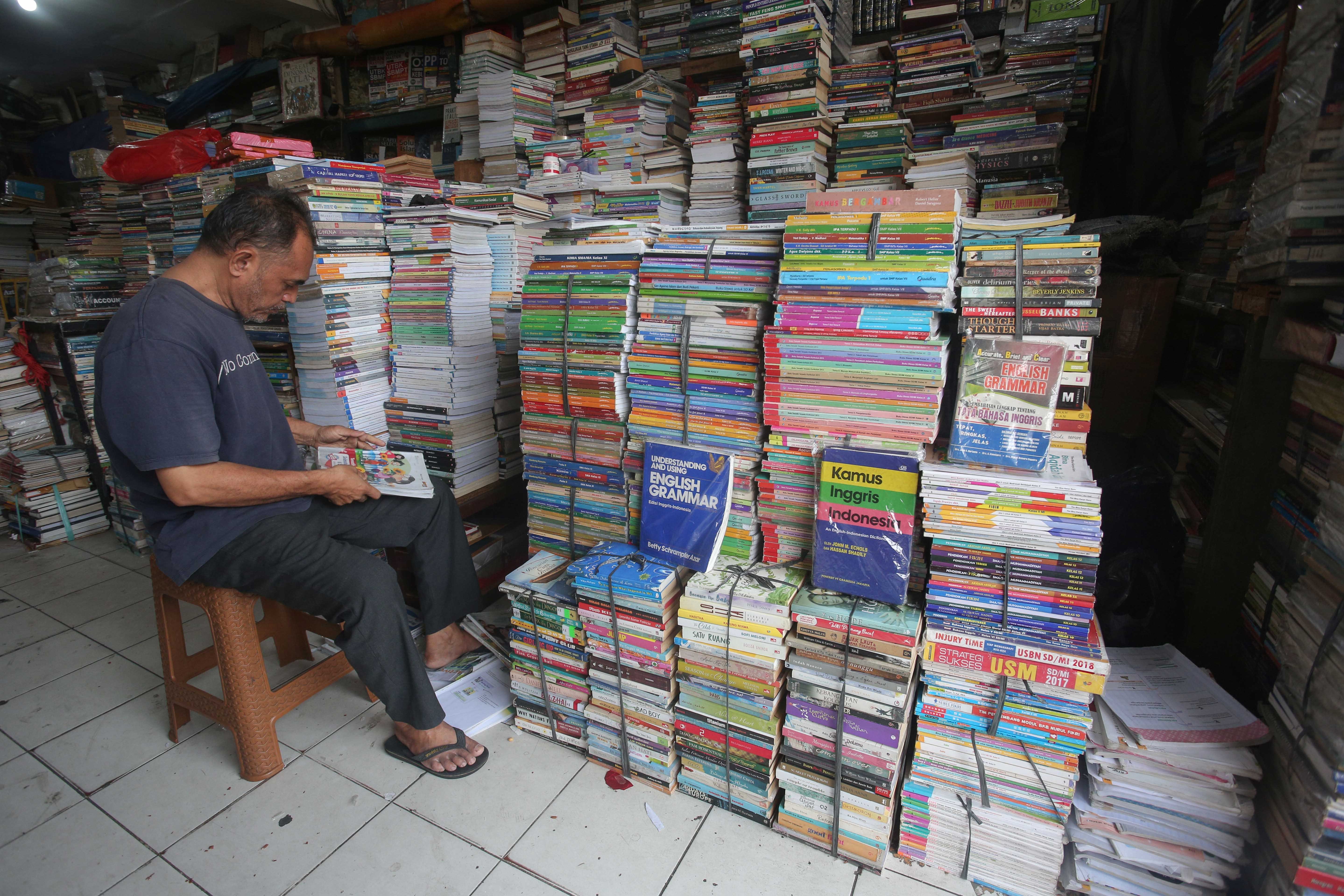 Pedagang merapikan buku yang dijual di Pasar Buku Kwitang, Jakarta Pusat, Rabu (24/7/2024). Berdasarkan penuturan pedagang, berkembangnya teknologi membuat masyarakat beralih dari membaca buku fisik ke digital sehingga penjualan buku di pasar tersebut mengalami penurunan yang cukup signifikan.