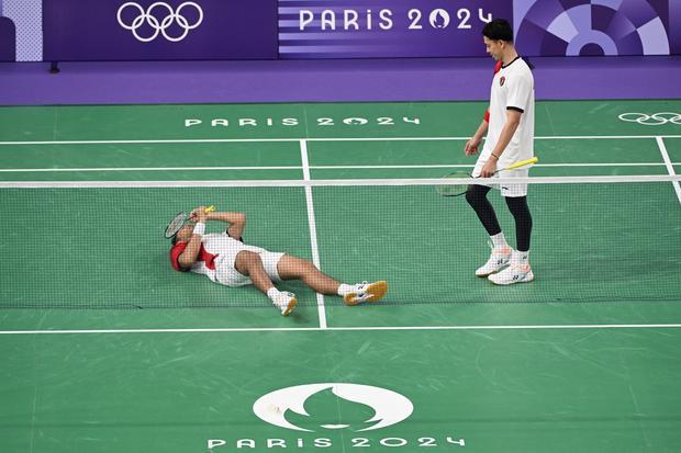 Pebulu tangkis ganda putra Indonesia Fajar Alfian (kiri) merebahkan diri di lapangan disaksikan rekannya Muhammad Rian Ardianto usai kalah dari ganda putra China Liang Wei Keng/Wang Chang pada babak perempat final Olimpiade Paris 2024 di Porte De La Chapella Arena, Paris, Prancis, Kamis (1/8/2024). Muhammad Rian Ardianto/Fajar Alfian kalah dari Liang Wei Keng/Wang Chang dengan skor 22-24, 20-22.