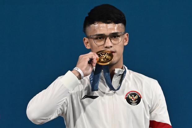 Lifter Indonesia Rizki Juniansyah berpose dengan medali emasnya usai upacara pengalungan medali kelas 73 kg putra Olimpiade Paris 2024 di South Paris Arena, Paris, Prancis, Kamis (8/8/2024). Rizki meraih medali emas setelah berhasil meraih total angkatan 354 kilogram sehingga menduduki peringkat pertama dari 12 lifter yang turut serta dalam nomor tersebut.