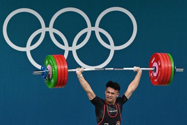 Lifter Indonesia Rizki Juniansyah melakukan angkatan clean and jerk dalam kelas 73 kg putra Olimpiade Paris 2024 di South Paris Arena, Paris, Prancis, Kamis (8/8/2024). Rizki meraih medali emas setelah berhasil meraih total angkatan 354 kilogram sehingga menduduki peringkat pertama dari 12 lifter yang turut serta dalam nomor tersebut.