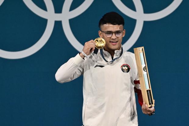 Lifter Indonesia Rizki Juniansyah berpose dengan medali emasnya usai upacara pengalungan medali kelas 73 kg putra Olimpiade Paris 2024 di South Paris Arena, Paris, Prancis, Kamis (8/8/2024). Rizki meraih medali emas setelah berhasil meraih total angkatan 354 kilogram sehingga menduduki peringkat pertama dari 12 lifter yang turut serta dalam nomor tersebut.