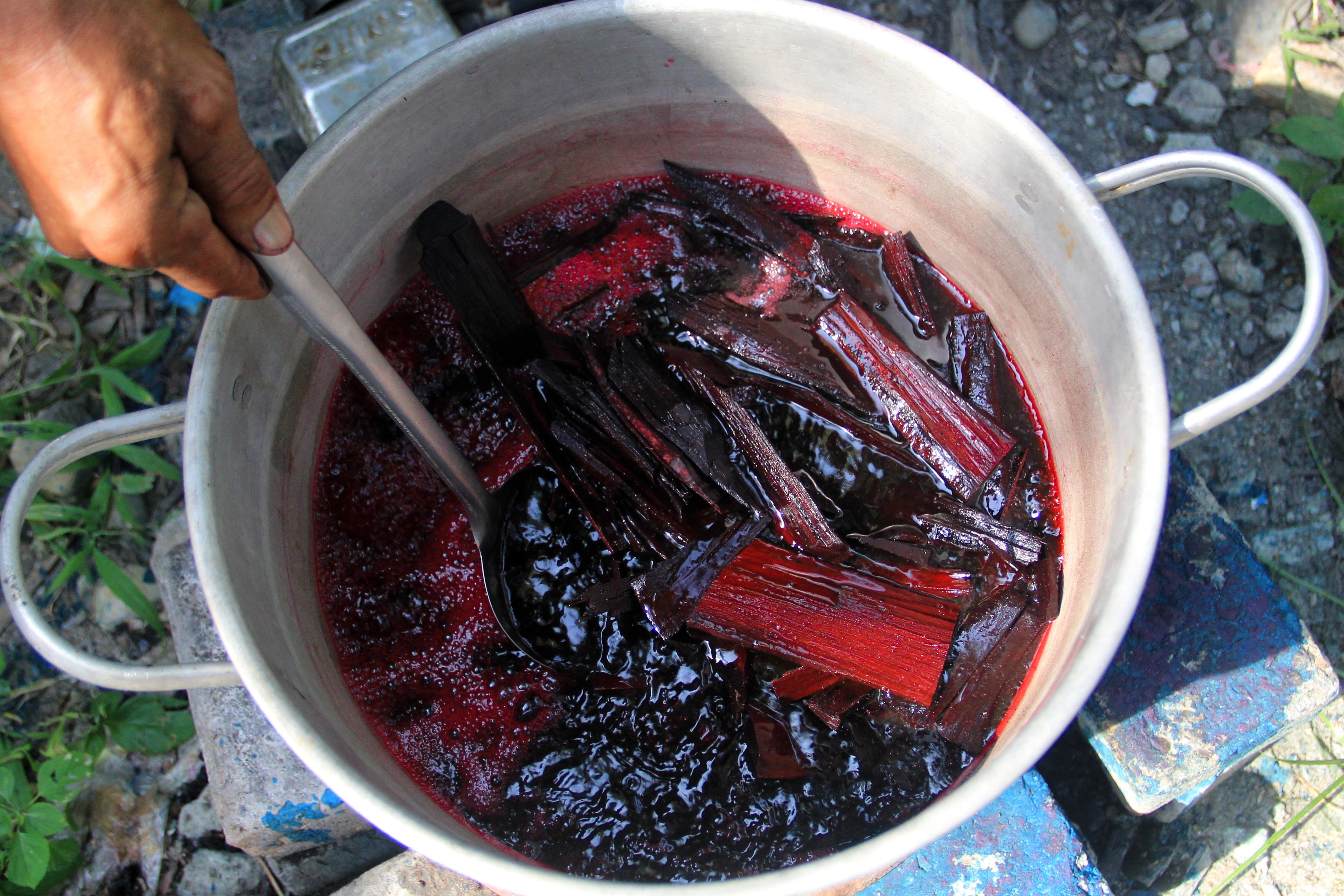 Perajin merebus ranting mangrove untuk digunakan sebagai pewarna batik di Desa Pematang Johar, Deli Serdang, Sumatra Utara.