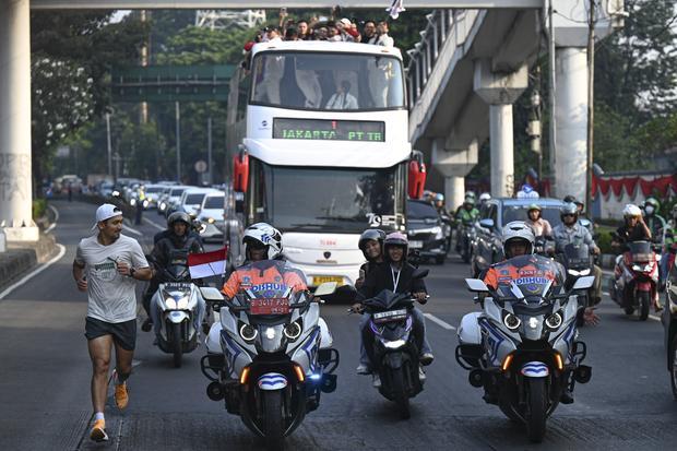 Aktor Ibnu Jamil (kiri) berlari mengiringi arak-arakan atlet dengan bus tingkat terbuka dari Kantor Kemenpora menuju Istana Negara di Jakarta, Kamis (15/8/2024). Arak-arakan yang diikuti atlet dan ofisial itu untuk menyambut atlet yang telah mempersembahkan dua medali emas melalui Rizki Juniansyah dari cabang olahraga angkat besi dan pemanjat tebing Veddriq Leonardo, serta satu perunggu melalui pebulu tangkis Gregoria Mariska Tunjung pada OIimpiade Paris 2024.