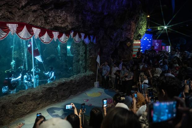 Sejumlah pengunjung menyaksikan penyelam mengibarkan bendera Merah Putih dalam gladi bersih memperingati HUT Ke-79 Kemerdekaan RI di Sea World Ancol, Jakarta, Kamis (15/8/2024). Dalam rangka memeriahkan HUT ke-79 RI, Ancol Taman Impian menggelar berbagai kegiatan dengan tema Merdekaria di seluruh unit rekreasi salah satunya yaitu pengibaran bendera Merah Putih di Sea World.