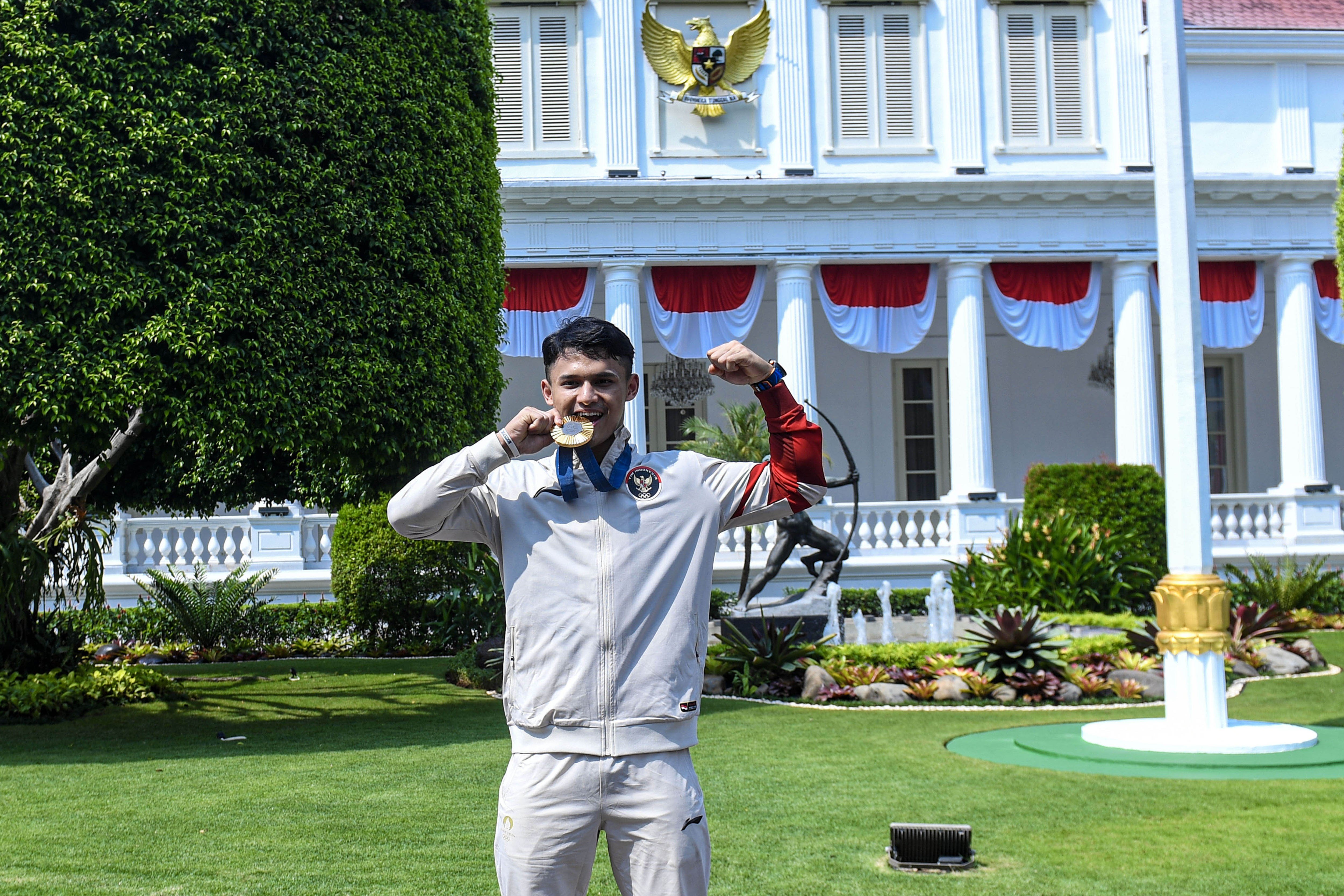 Lifter putra Rizki Juniansyah berpose usai mengikuti acara penyerahan bonus kepada kontingen Indonesia yang berlaga di Olimpiade Paris 2024 di halaman Istana Negara, Jakarta, Kamis (15/8/2024). Peraih medali emas pada nomor 73kg putra cabang angkat besi Olimpiade Paris 2024 itu mendapatkan bonus dari Presiden Joko Widodo sebesar Rp6 miliar. 