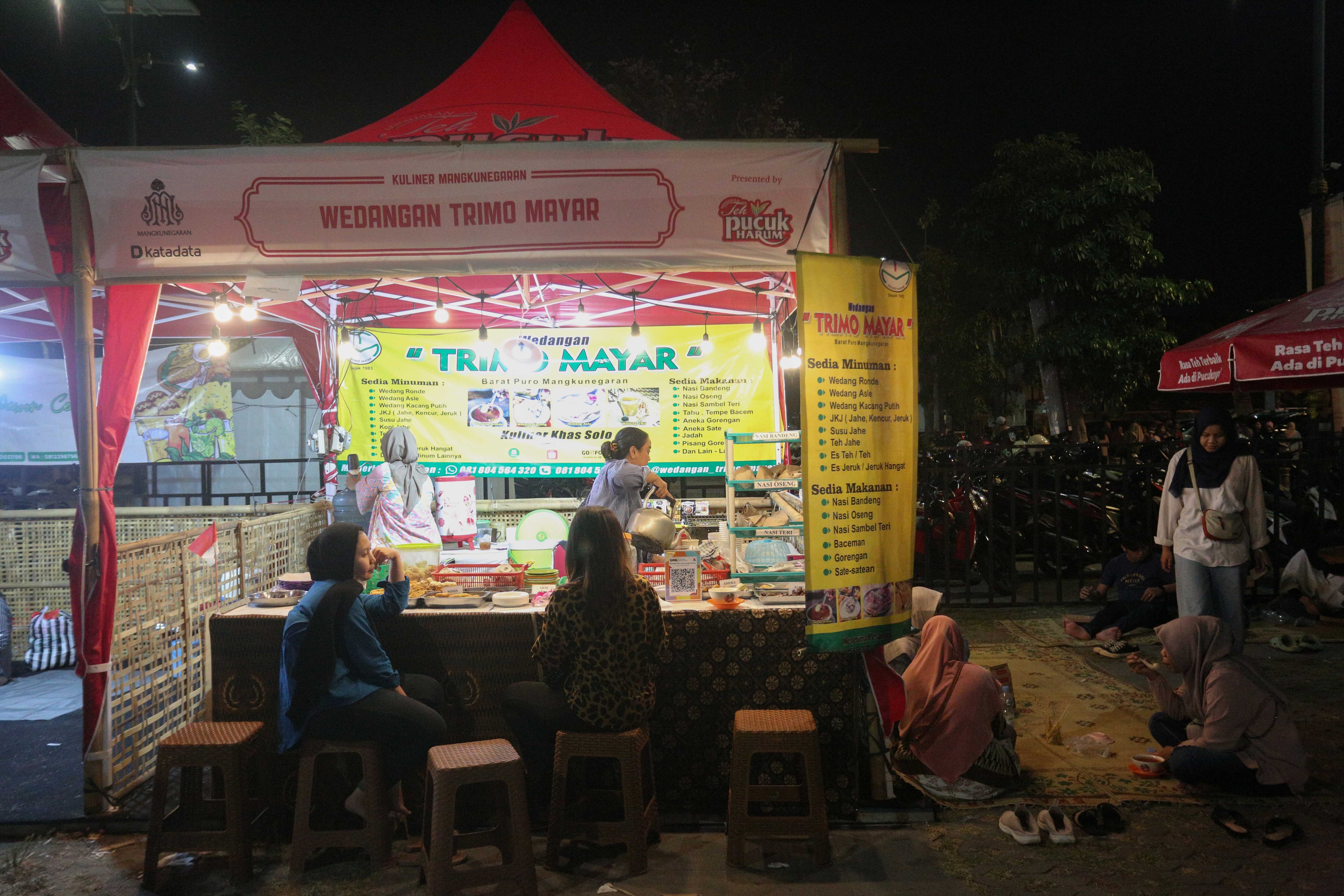 Pengunjung menikmati makanan di stan Wedangan Trimo Mayar saat Festival Kuliner Dua Generasi di Pamedan Pura Mangkunegaran, Solo, Jawa Tengah, Sabtu (17/8/2024). Festival kuliner yang merupakan salah satu rangkaian acara pada 