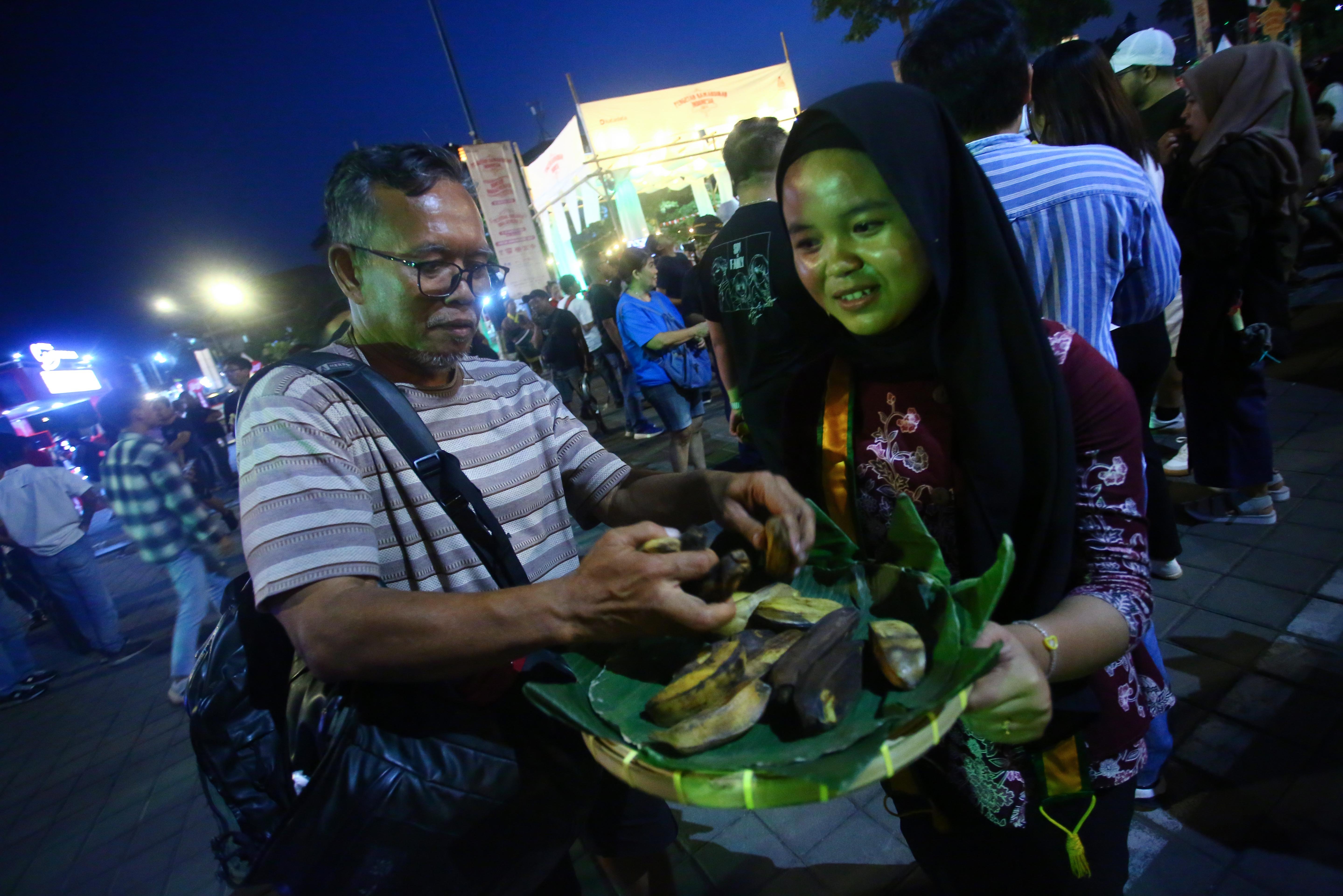 Pengunjung mengambil makanan yang dibagikan saat pembukaan Festival Kuliner Dua Generasi di Pamedan Pura Mangkunegaran, Solo, Jawa Tengah, Sabtu (17/8/2024). Festival kuliner yang merupakan salah satu rangkaian acara pada 