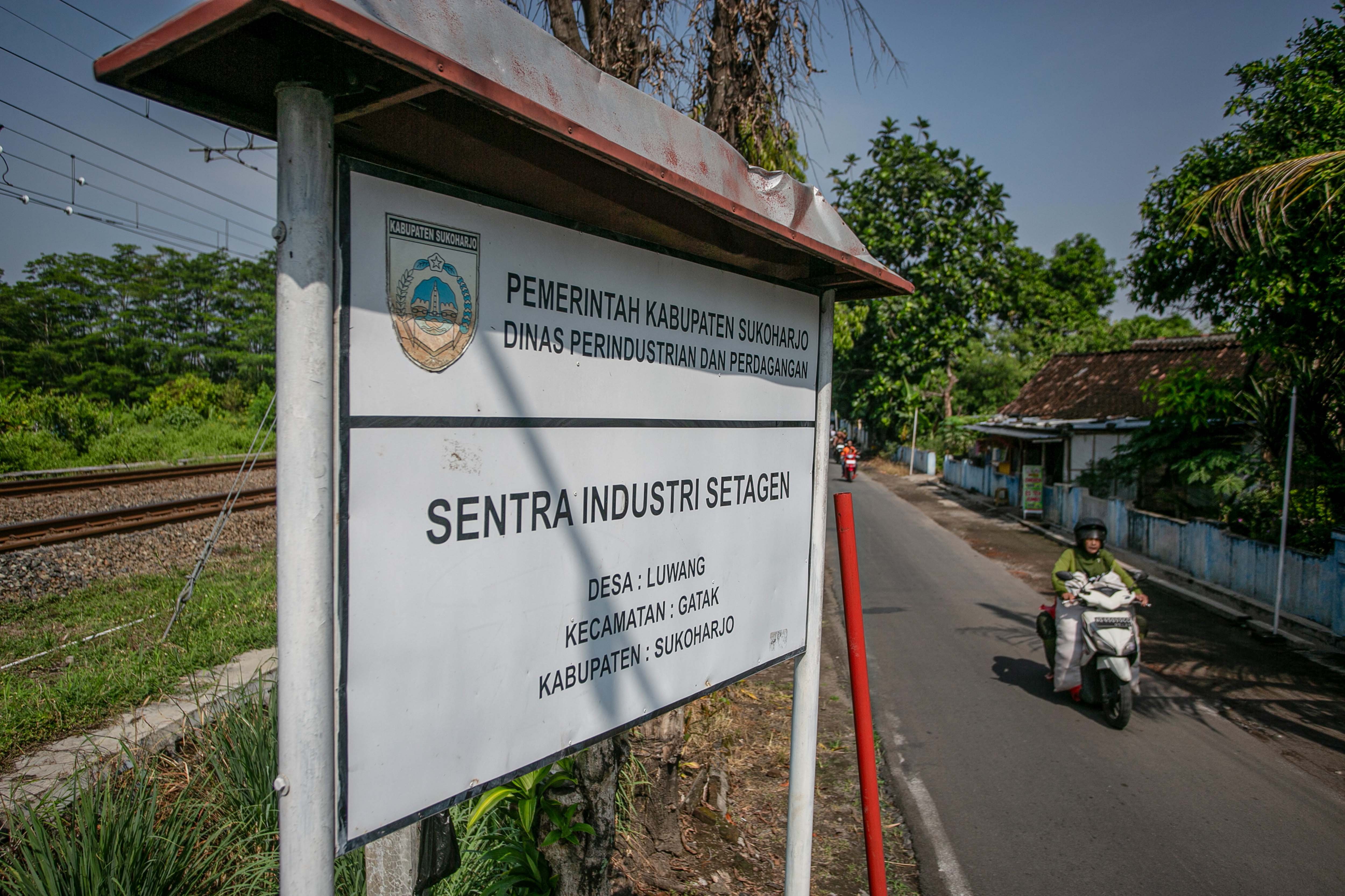 Pengendara sepeda motor melaju di depan papan penanda kawasan sentra industri setagen di Desa Luwang, Gatak, Sukoharjo, Jawa Tengah.