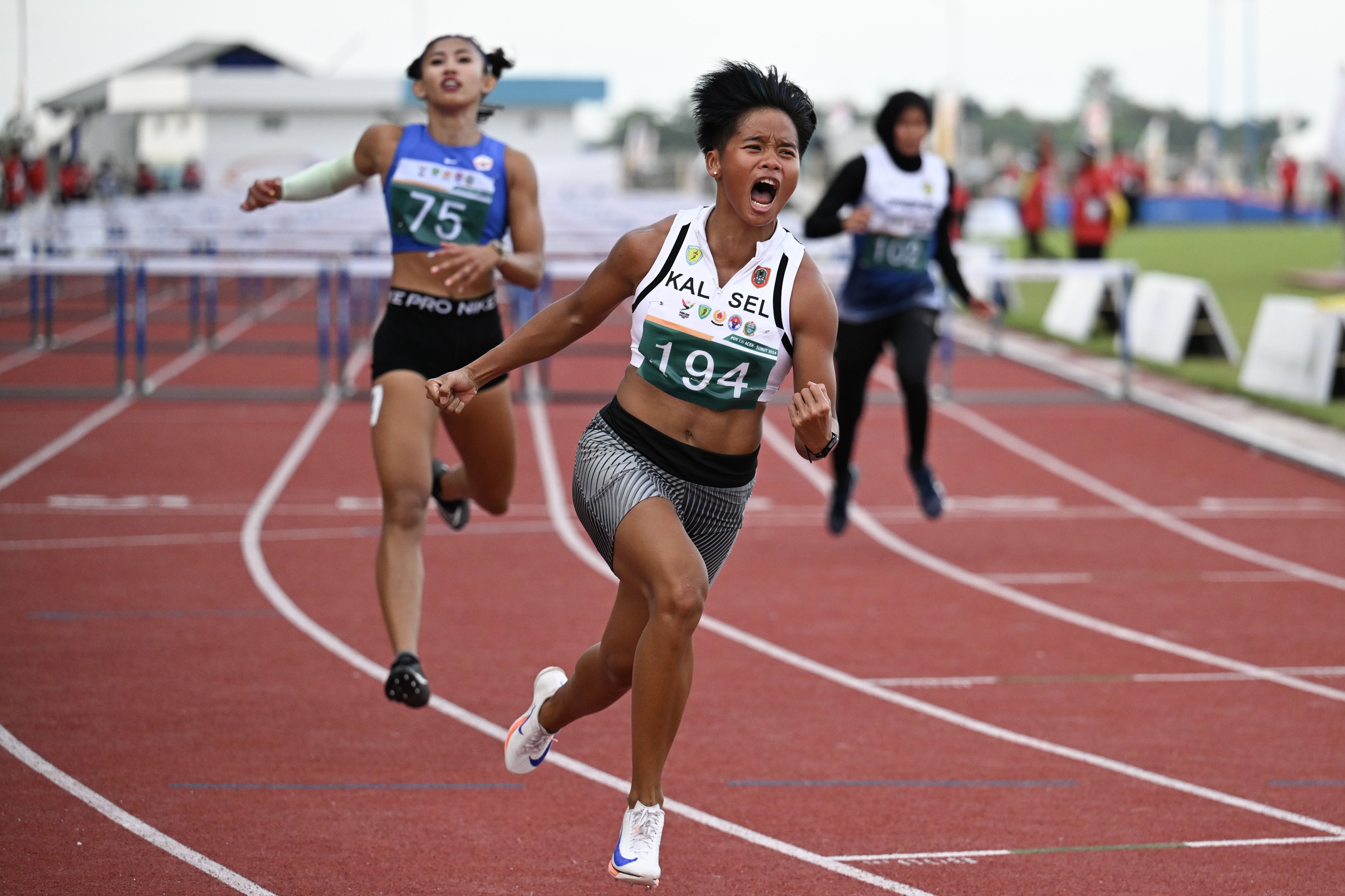 Pelari Kalimantan Selatan Dina Aulia (tengah) beradu kecepatan dengan pelari DKI Jakarta Emilia Nova (kiri) dan pelari Jawa Barat Devi Aprilian (kanan) pada final nomor lari gawang 100 meter putri PON XXI Aceh-Sumut di Stadion Madya Atletik Sumut Sport Centre, Deli Serdang, Sumatera Utara, Kamis (12/9/2024). Dina Aulia meraih medali emas dengan catatan waktu 13,16 detik, medali perak diraih Emilia Nova dengan waktu 13,43 detik, sedangkan medali perunggu diraih Yunitasari Mariska dengan waktu 14,38 detik. 