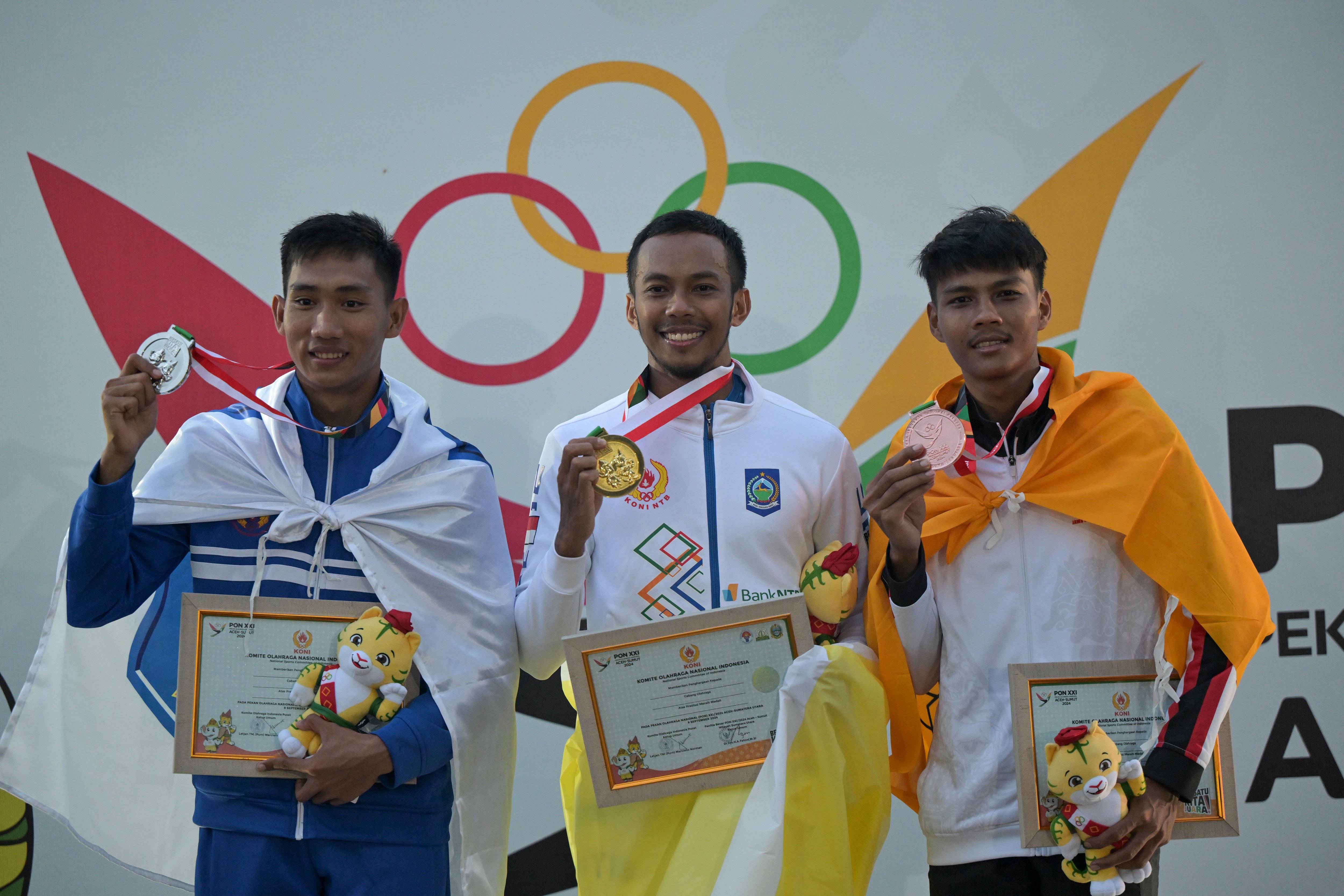 Atlet lompat jauh NTB Sapwaturrahman (tengah), atlet Bangka Belitung Ahmad Ambali (kiri), atlet Jawa Tengah Arifianto (kanan) berfoto bersama saat upacara penghargaan pemenang final lompat jauh putra PON XXI Aceh-Sumut 2024 di Stadion Madya Atletik Sumut Sport Center, Deli Serdang, Sumatera Utara, Jumat (13/9/2024). 