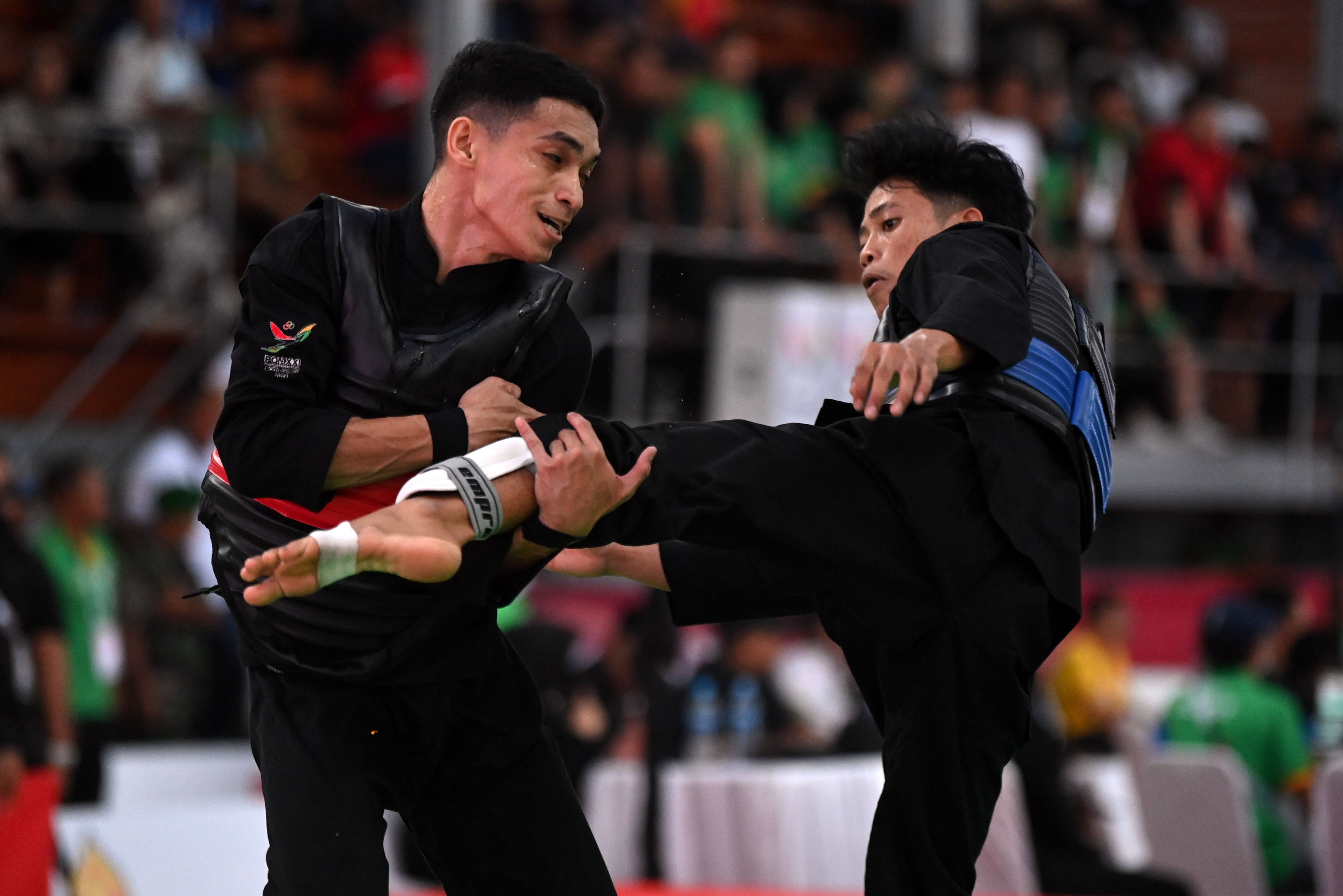 Pesilat NTT Muhammad Zikri (kiri) menahan tendangan dari pesilat Bali I Kadek Astawa (kanan) pada babak perempat final kategori tanding kelas B 50-55 kilogram putra, Pencak Silat PON XXI Aceh-Sumut 2024 di GOR Veteran Dinas Pemuda dan Olahraga Sumatera Utara (Disporasu), Medan, Sumatera Utara, Selasa (10/9/2024). Pesilat NTT menang atas pesilat Bali dengan skor 44-22. 