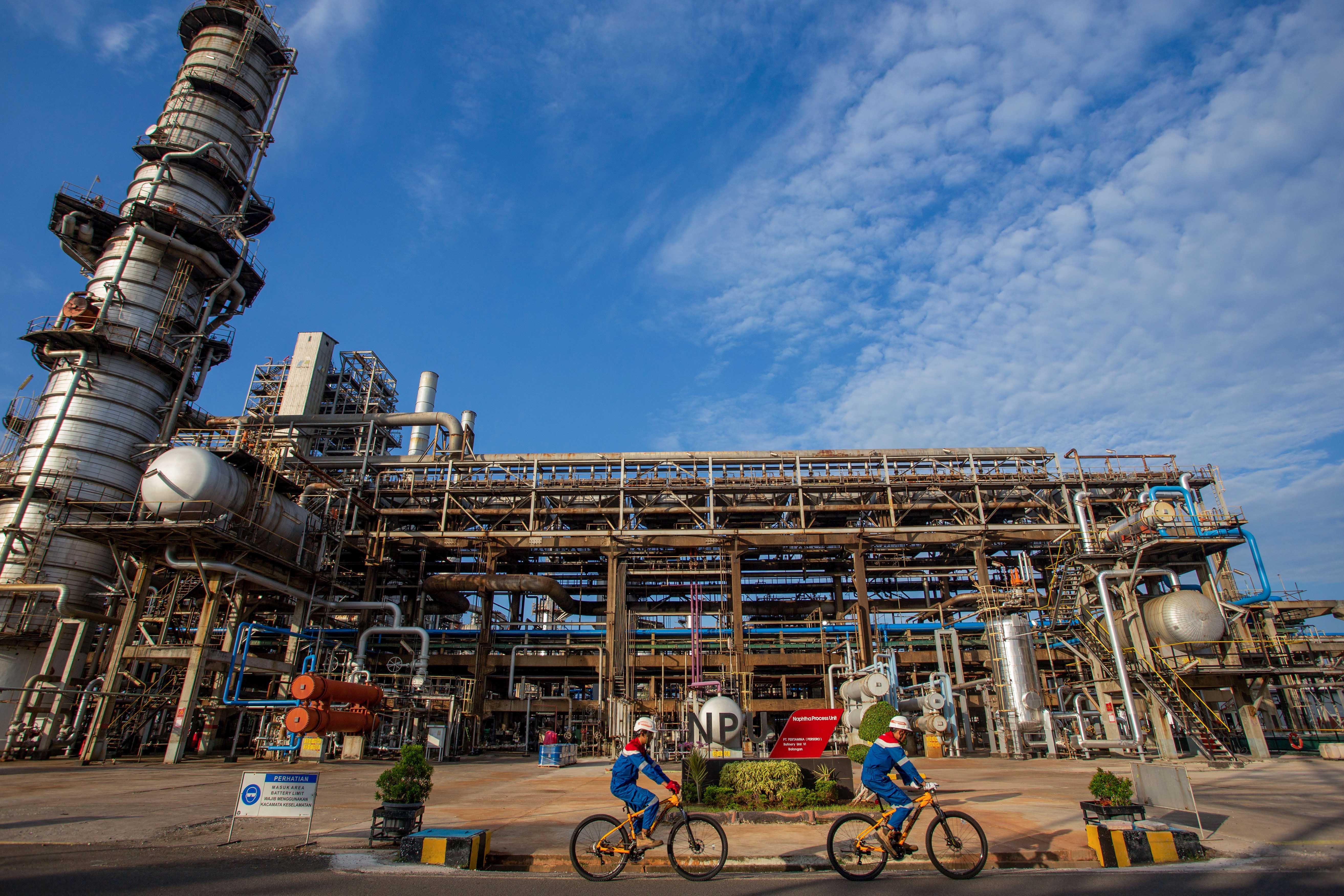 Dua petugas Pertamina bersepeda di sekitar area Naphtha Processing Unit (NPU) di Kilang Pertamina Internasional (KPI) Unit Balongan di Indramayu, Jawa Barat.