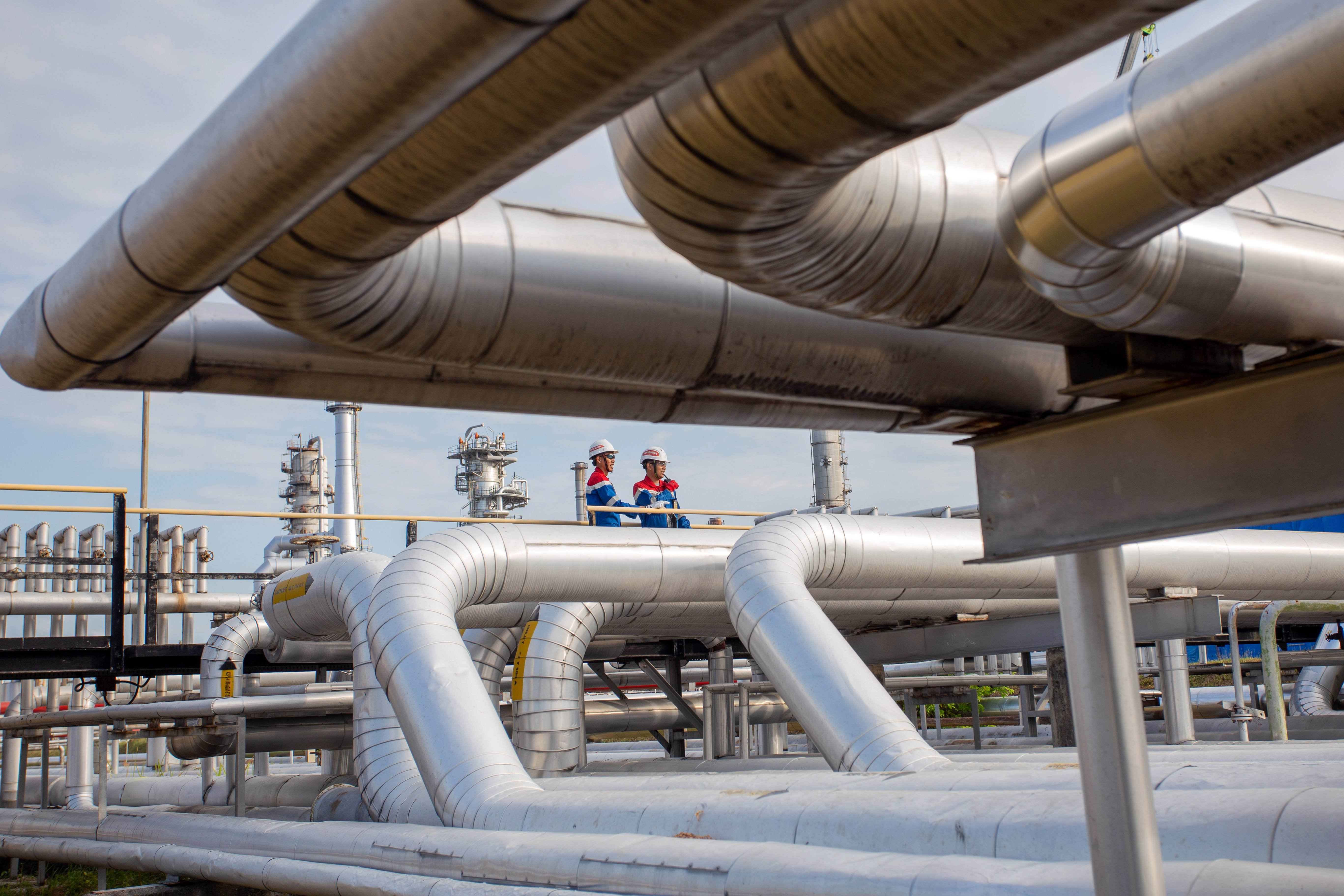 Dua petugas Pertamina memeriksa pipa jalur distribusi BBM yang akan dikirim ke terminal bahan bakar untuk kebutuhan Jakarta, banten dan Jawa barat di Kilang Pertamina Internasional (KPI) Unit Balongan di Indramayu, Jawa Barat.