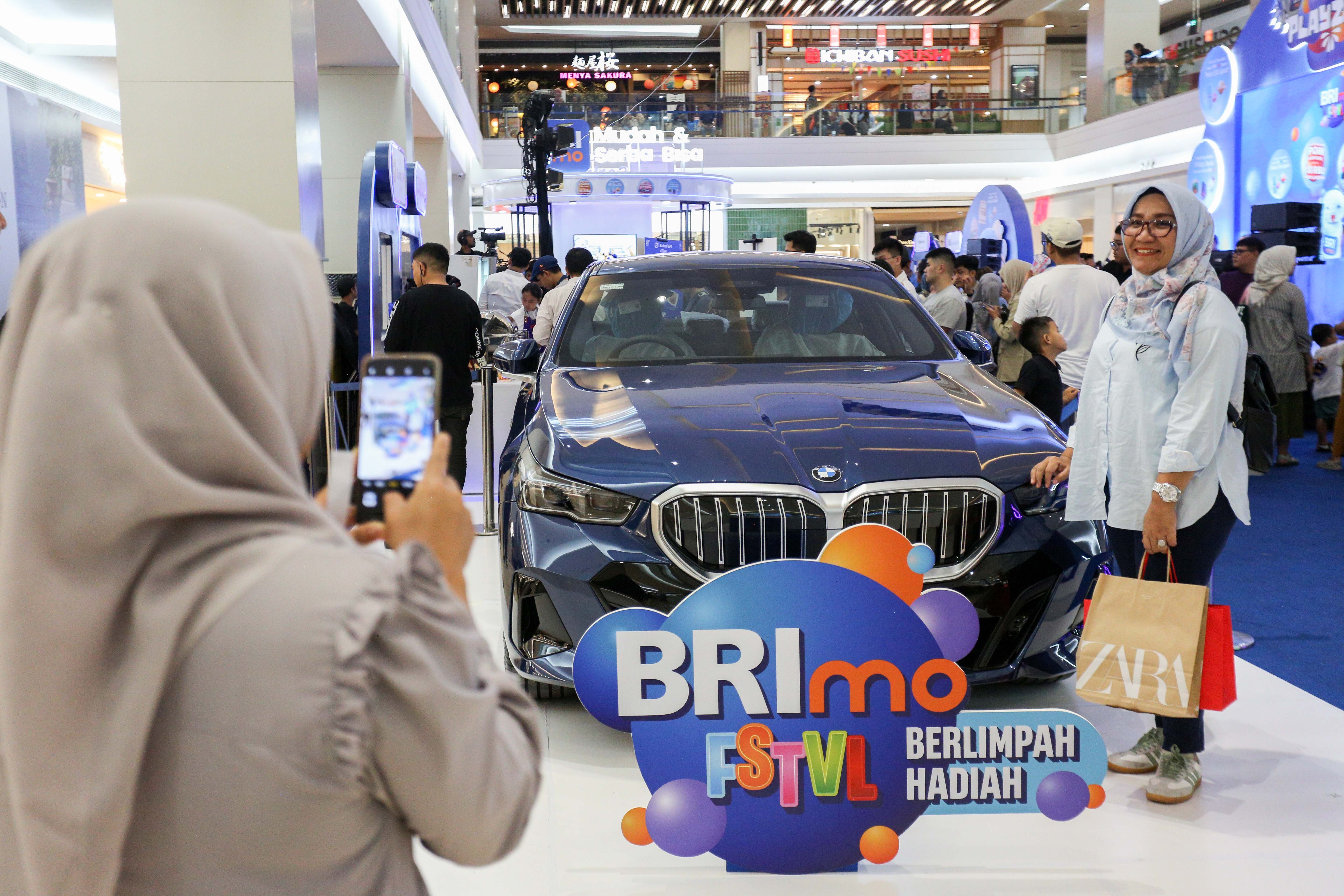 Pengunjung berfoto bersama Mobil BMW 520i M Sport saat acara BRImo FSTVL Playzone di Fashion Atrium, Mall Kota Kasablanka, Jakarta, Sabtu (12/10/2024). Dalam rangka memperkenalkan fitur terbaru dari super apps BRImo, PT Bank Rakyat Indonesia (Persero) Tbk menggelar BRImo FSTVL Playzone dengan berbagai kegiatan menarik mulai dari talk show, games corner hingga penampilan musik dari penyanyi Fabio Asher.