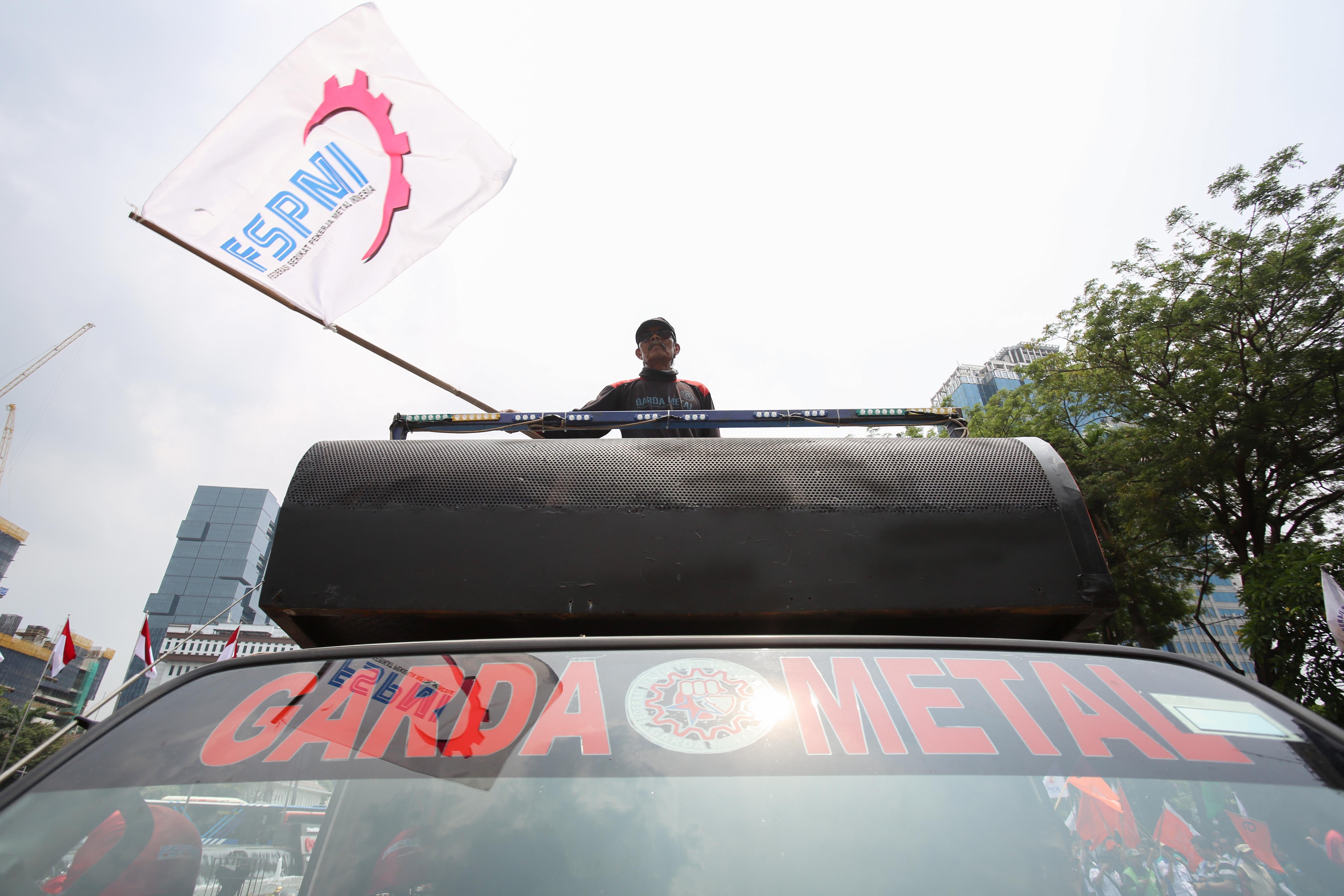 Seorang buruh mengibarkan bendera FSPMI saat mengikuti aksi unjuk rasa di kawasan Patung Kuda, Jakarta, Kamis (24/10/2024). Dalam aksinya tersebut buruh menuntut kepada pemerintah untuk menaikkan upah minimum tahun 2025 sebesar 8 hingga 10 persen. 