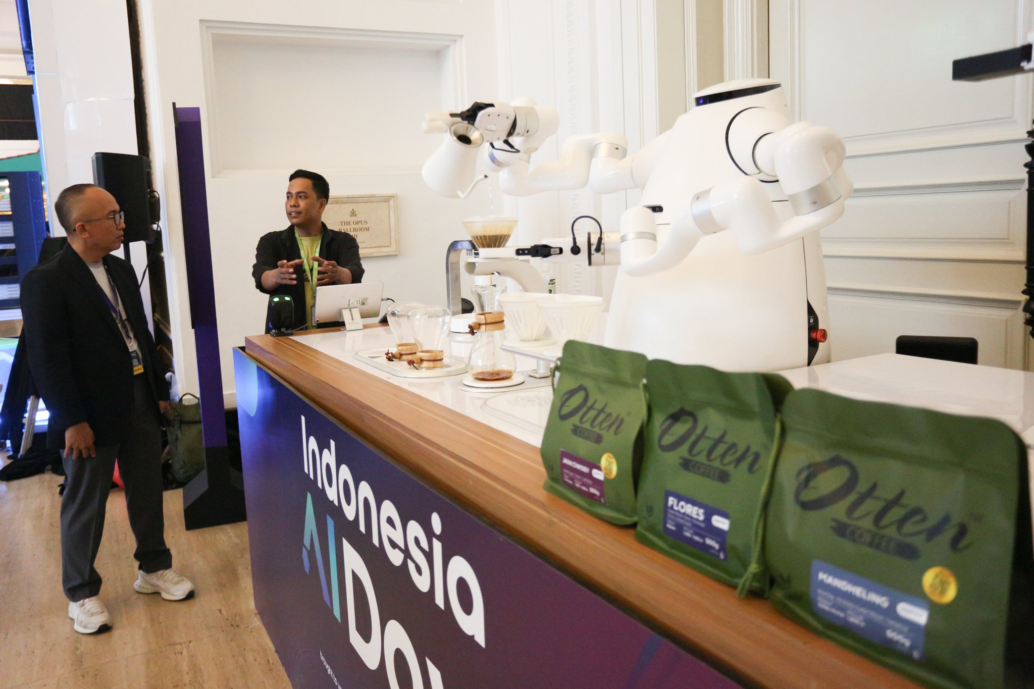 Petugas menyampaikan informasi mengenai teknologi robot pembuat kopi pada acara Indonesia AI Day di The Tribrata Hotel and Convention Center Darmawangsa, Jakarta, Kamis (14/11/2024). Mengusung tema Unleashing Indonesia’s AI Sovereignty, perhelatan tersebut merupakan forum untuk meningkatkan kesadaran dan pengetahuan, serta mendorong kolaborasi dalam mendukung kedaulatan kecerdasan buatan (AI) di Indonesia. 