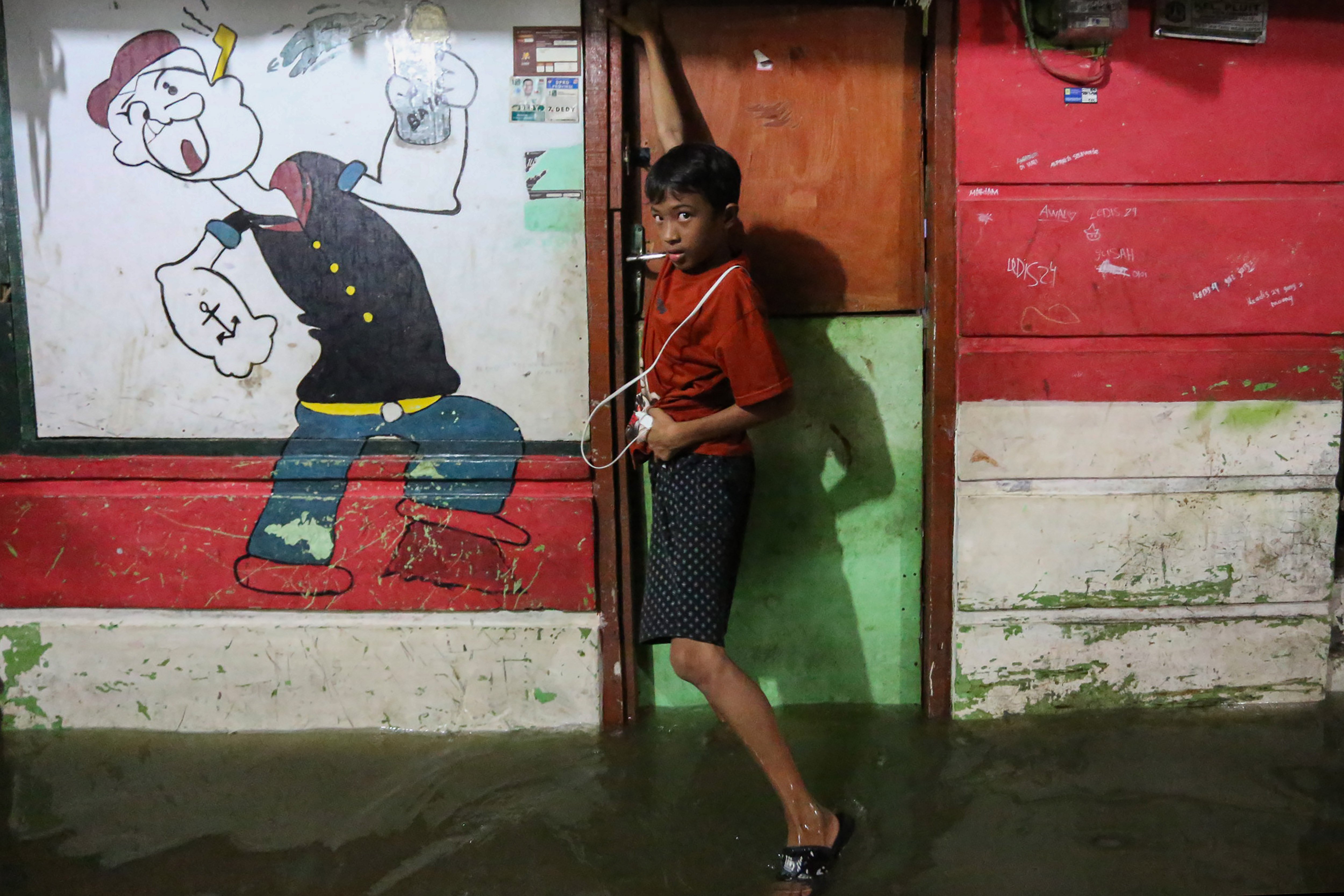 Seorang anak berada di depan rumahnya saat banjir rob di kawasan Muara Angke, Jakarta, Senin (18/11/2024). Menurut BPBD Jakarta rob yang melanda sejumlah wilayah di Jakarta Utara tersebut karena fenomena pasang maksimum air laut bersamaan dengan fase bulan baru yang berpotensi meningkatkan ketinggian pasang air laut maksimum berupa banjir pesisir di wilayah pesisir utara Jakarta. 