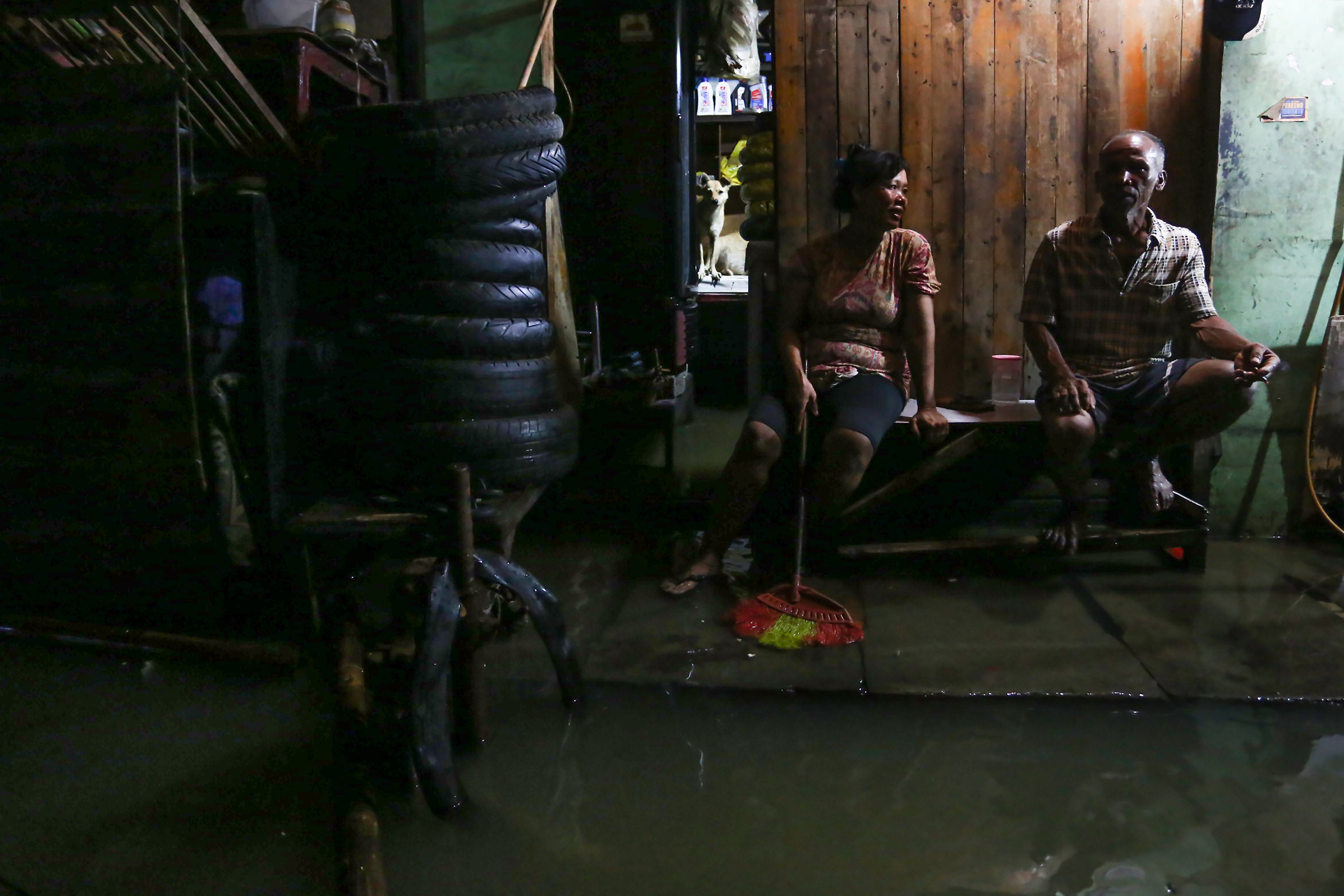 Dua warga duduk di depan rumahnya saat banjir rob di kawasan Muara Angke, Jakarta, Senin (18/11/2024). Menurut BPBD Jakarta rob yang melanda sejumlah wilayah di Jakarta Utara tersebut karena fenomena pasang maksimum air laut bersamaan dengan fase bulan baru yang berpotensi meningkatkan ketinggian pasang air laut maksimum berupa banjir pesisir di wilayah pesisir utara Jakarta. 