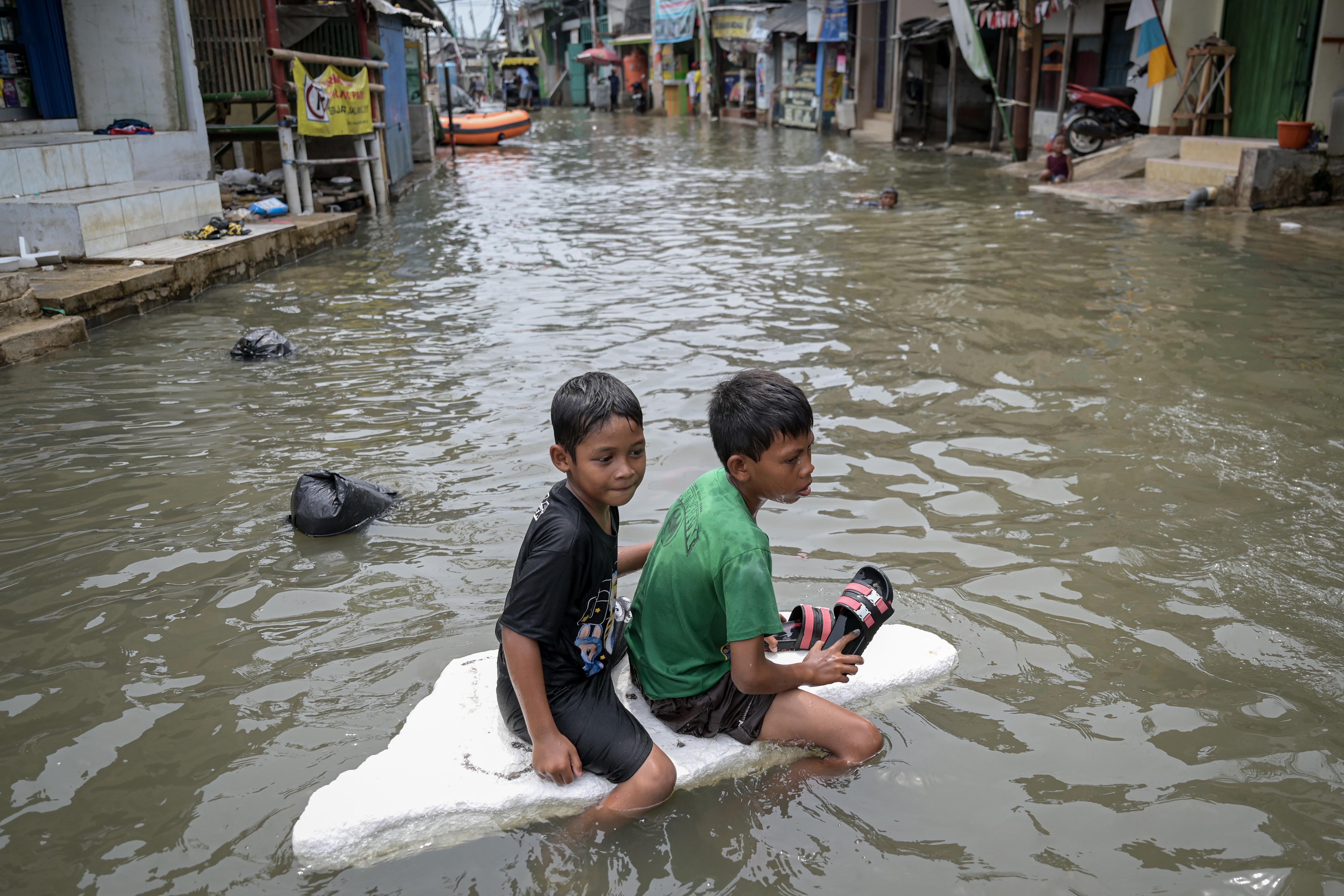 Dua anak bermain di tengah banjir rob di Muara Angke , Jakarta, Rabu (20/11/2024). Memasuki hari keenam, banjir setinggi hingga 50 sentimeter akibat pasangnya air laut tersebut diprediksi masih akan terjadi sampai 21 November 2024. 