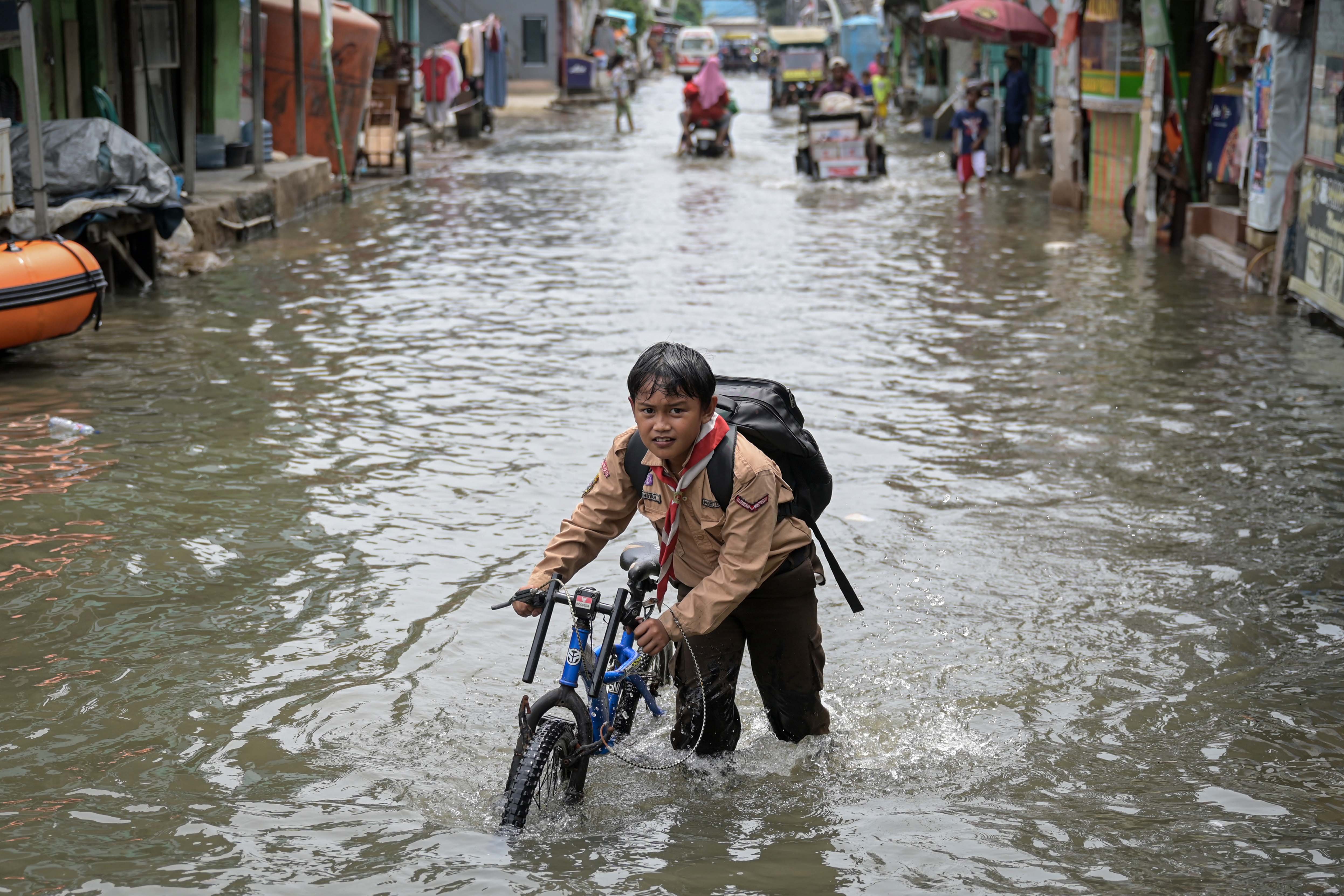 Seorang anak menuntun sepedanya di tengah banjir rob di Muara Angke , Jakarta, Rabu (20/11/2024). Memasuki hari keenam, banjir setinggi hingga 50 sentimeter akibat pasangnya air laut tersebut diprediksi masih akan terjadi sampai 21 November 2024. 