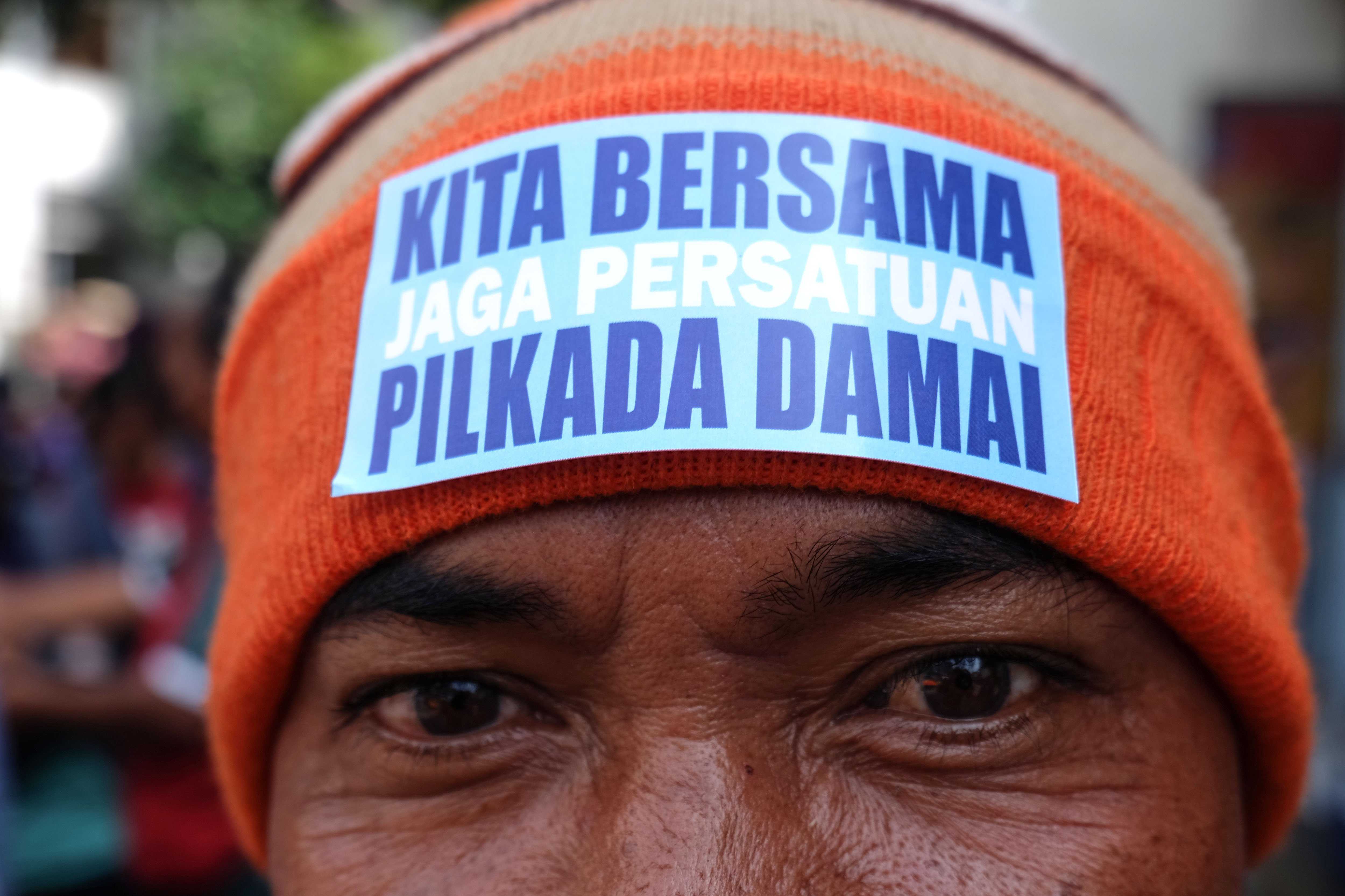 Warga menunjukkan stiker bertema pilkada damai dan demokratis di penutup kepalanya saat aksi di kawasan Pasar Gede Solo, Jawa Tengah, Selasa (26/11/2024). Aksi tersebut untuk mengajak warga menggunakan hak pilihnya dalam Pemilihan Kepala Daerah (Pilkada) serentak pada Rabu (27/11) dan berusaha mewujudkan berlangsungnya pilkada yang damai guna menjaga persatuan seusai pemungutan suara.