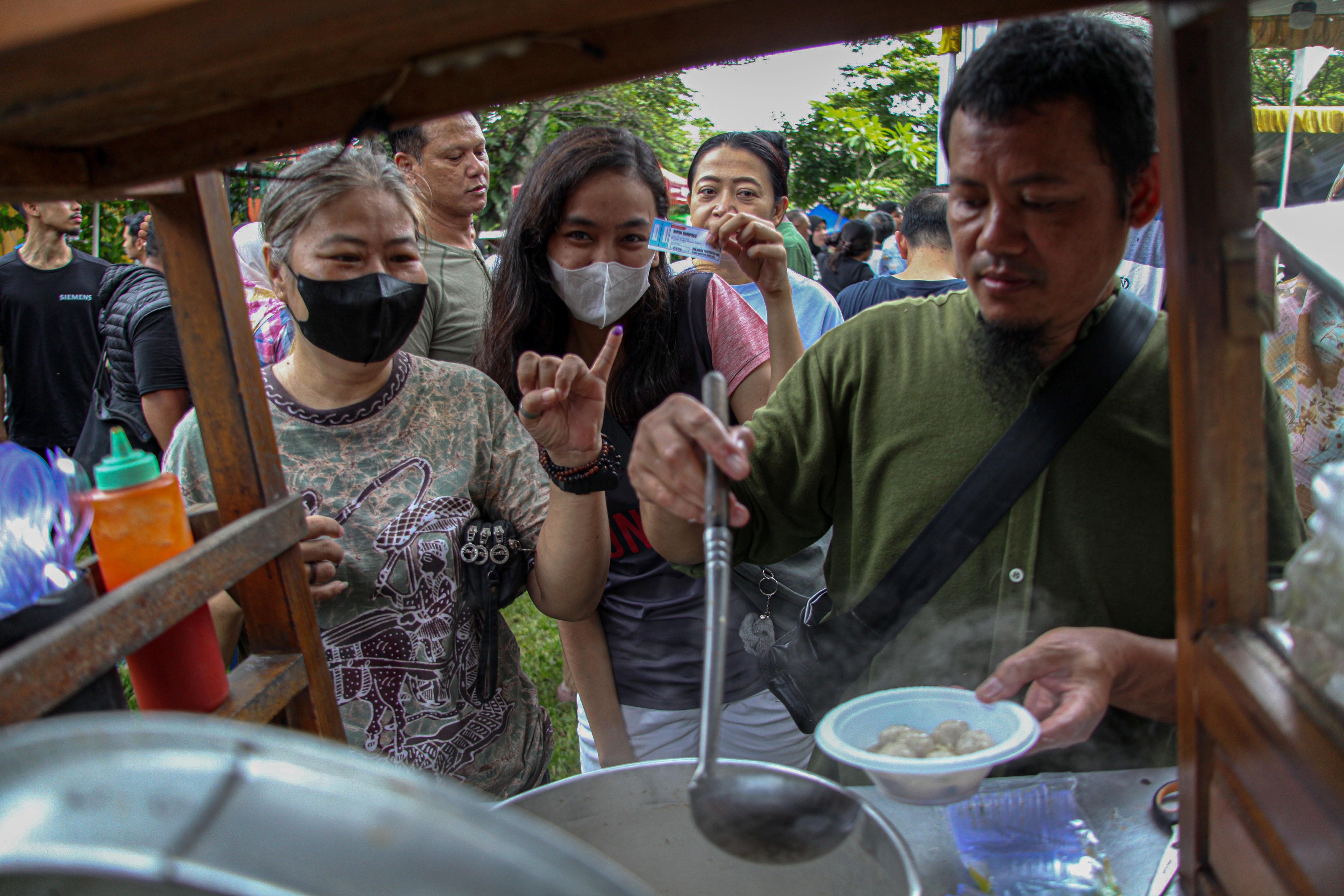 Warga antre untuk mengambil makan dan minum gratis usai menggunakan hak pilihnya di Perumahan Nirwana Estate, Pakansari, Kabupaten Bogor, Jawa Barat, Rabu (27/11/2024). KPPS setempat menyediakan makan dan minuman gratis kepada pemilih usai menggunakan hak suaranya guna menarik minat warga datang ke TPS dan menyalurkan hak pilihnya. 